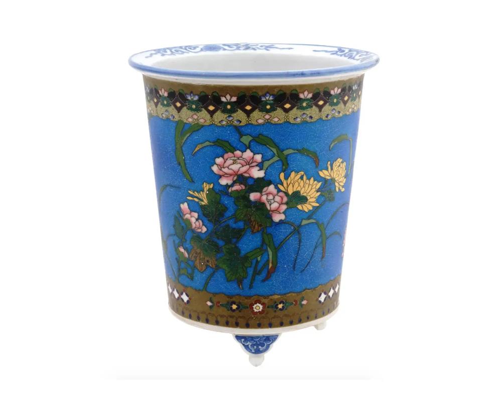 An antique Japanese, late Meiji era, footed and hand enamel on porcelain planter. Circa: late 19th century to early 20th century. The exterior of the planter is adorned with polychrome images of blossoming flowers on blue ground made in the