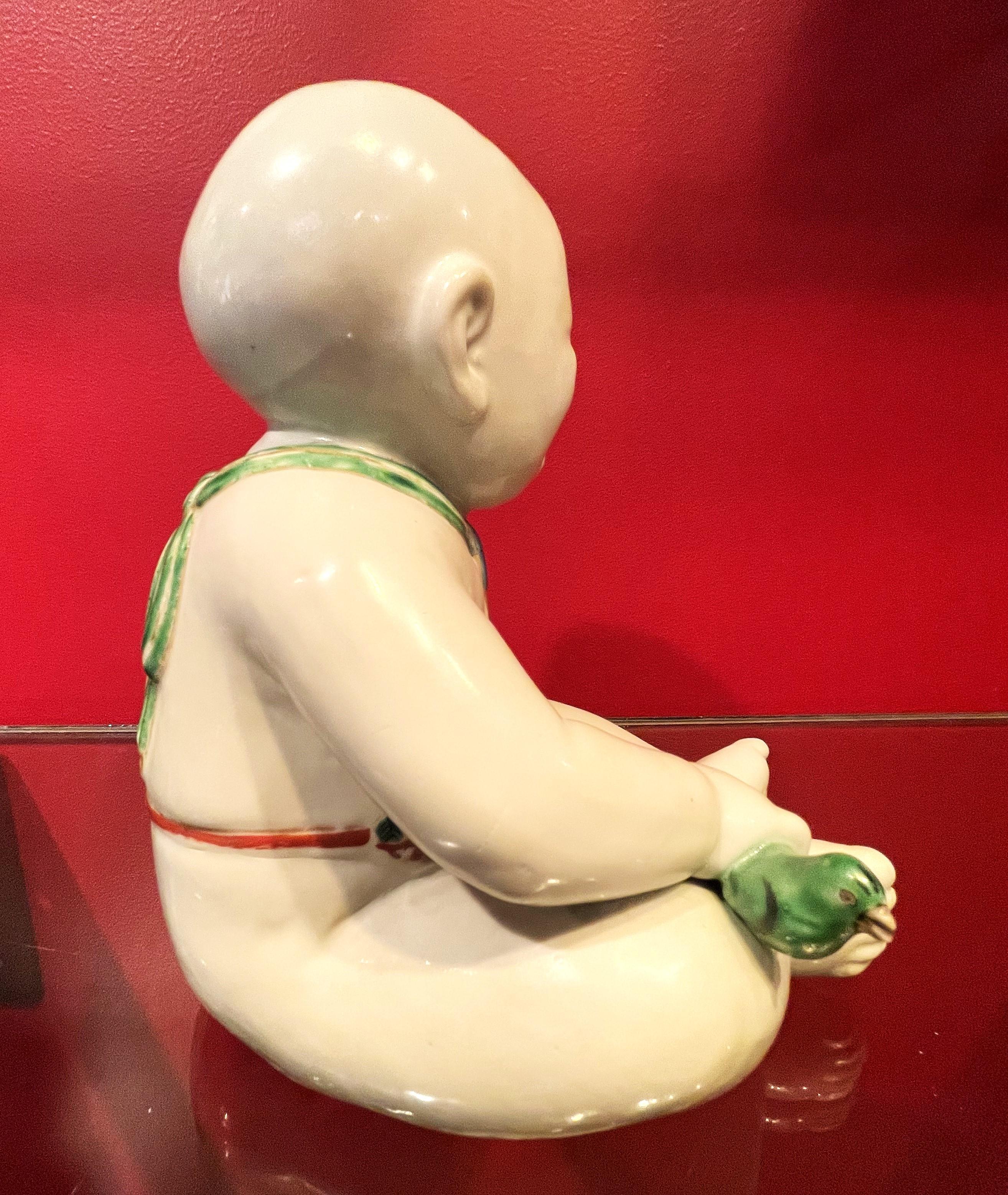 Painted Japanese Meiji Porcelain Figurine of Boy Holding a Green Whistle Bird, Ca. 1890 For Sale
