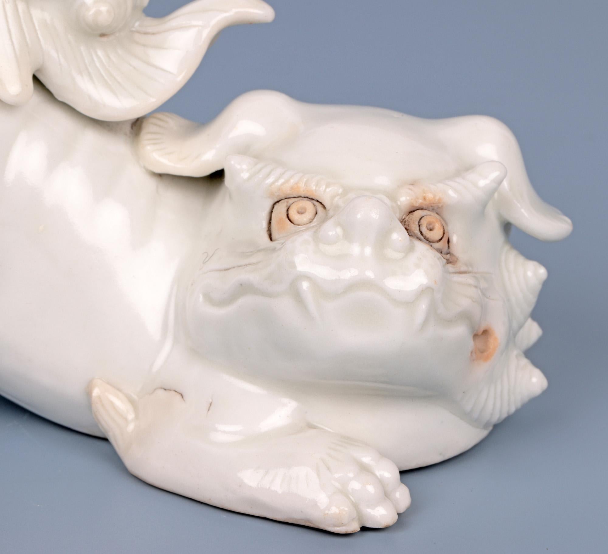 A stylish Japanese Meiji Hirado porcelain figure of a Shishi dating from the early 19th century. The well modelled and detailed figure rests its head on its front paws with its head turned to one side and with its rear legs raised in a playful pose.