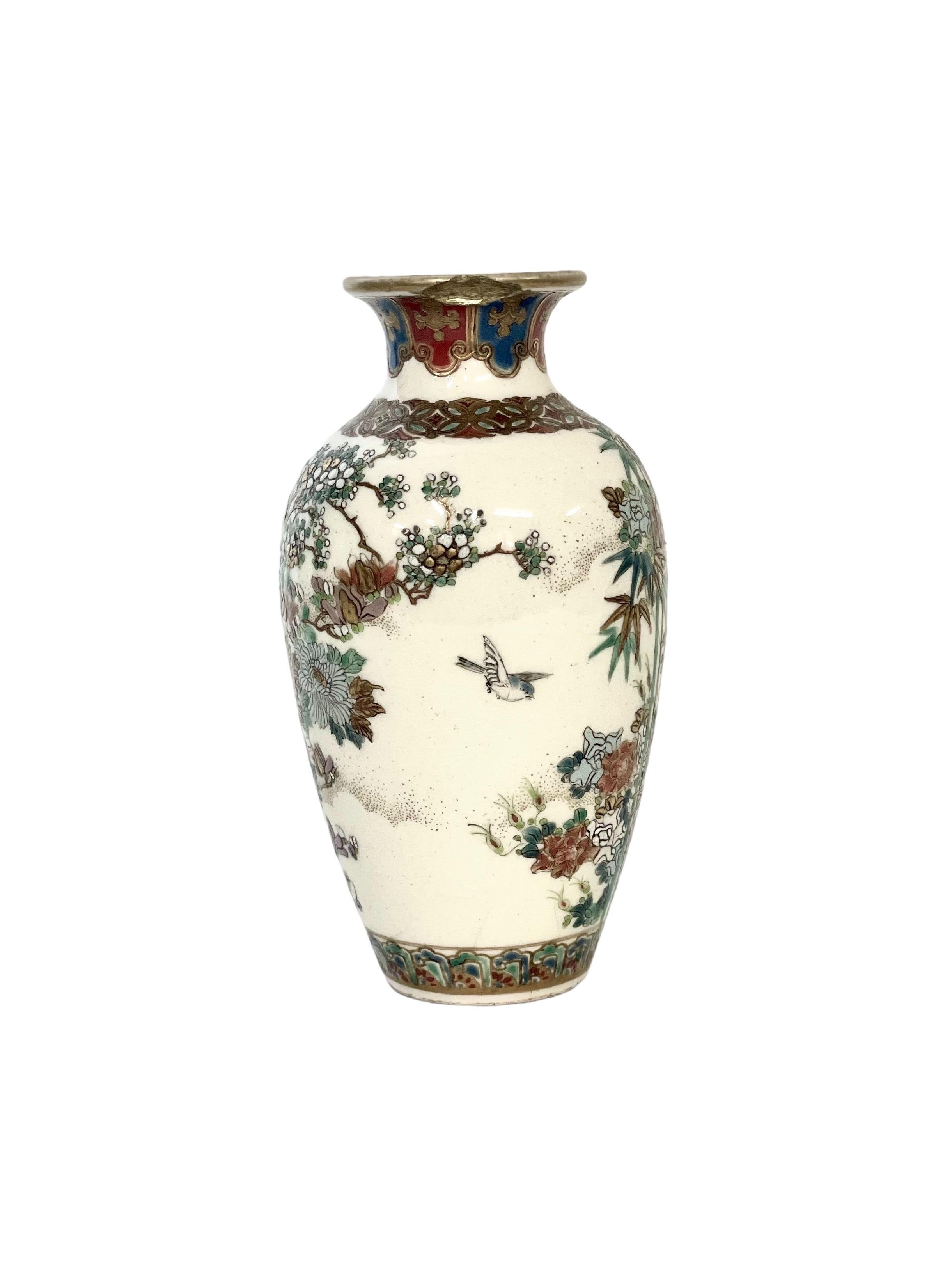 Un petit et magnifique vase balustre en céramique décoré à la main, peint tout autour de motifs japonais traditionnels, y compris la flore indigène, les oiseaux et les tiges de bambou sur un fond émaillé crème. La palette de couleurs est audacieuse