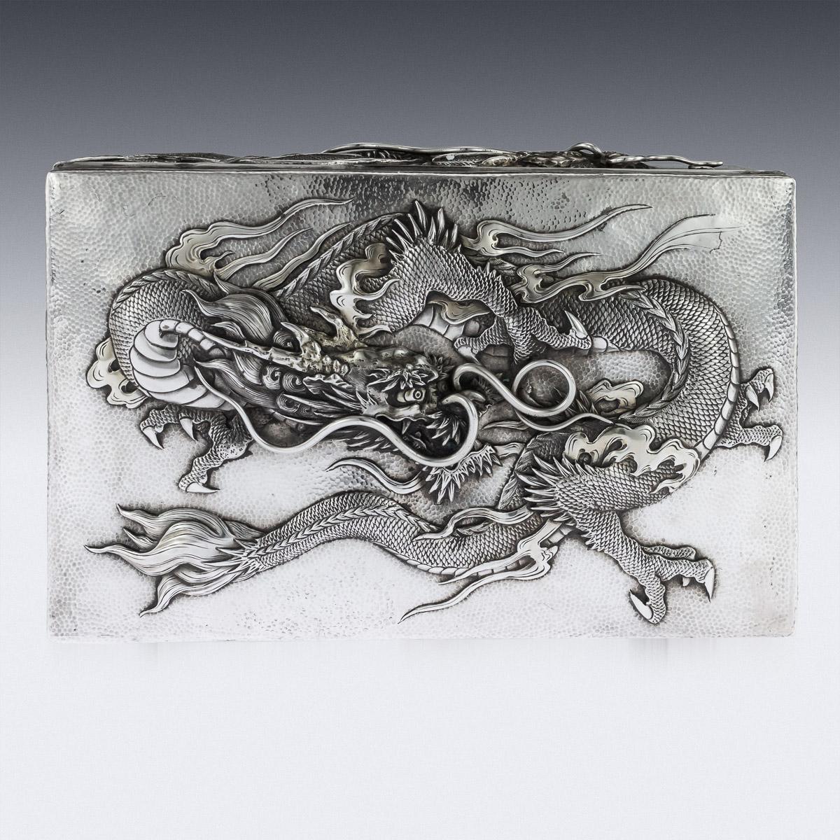 Antique early 20th century Japanese Meiji period solid silver box, double skinned body, sides and lid are embossed in high-relief with dragons and applied with flowing whiskers on hand-hammered ground, dark wood lined base and interior. Hallmarked