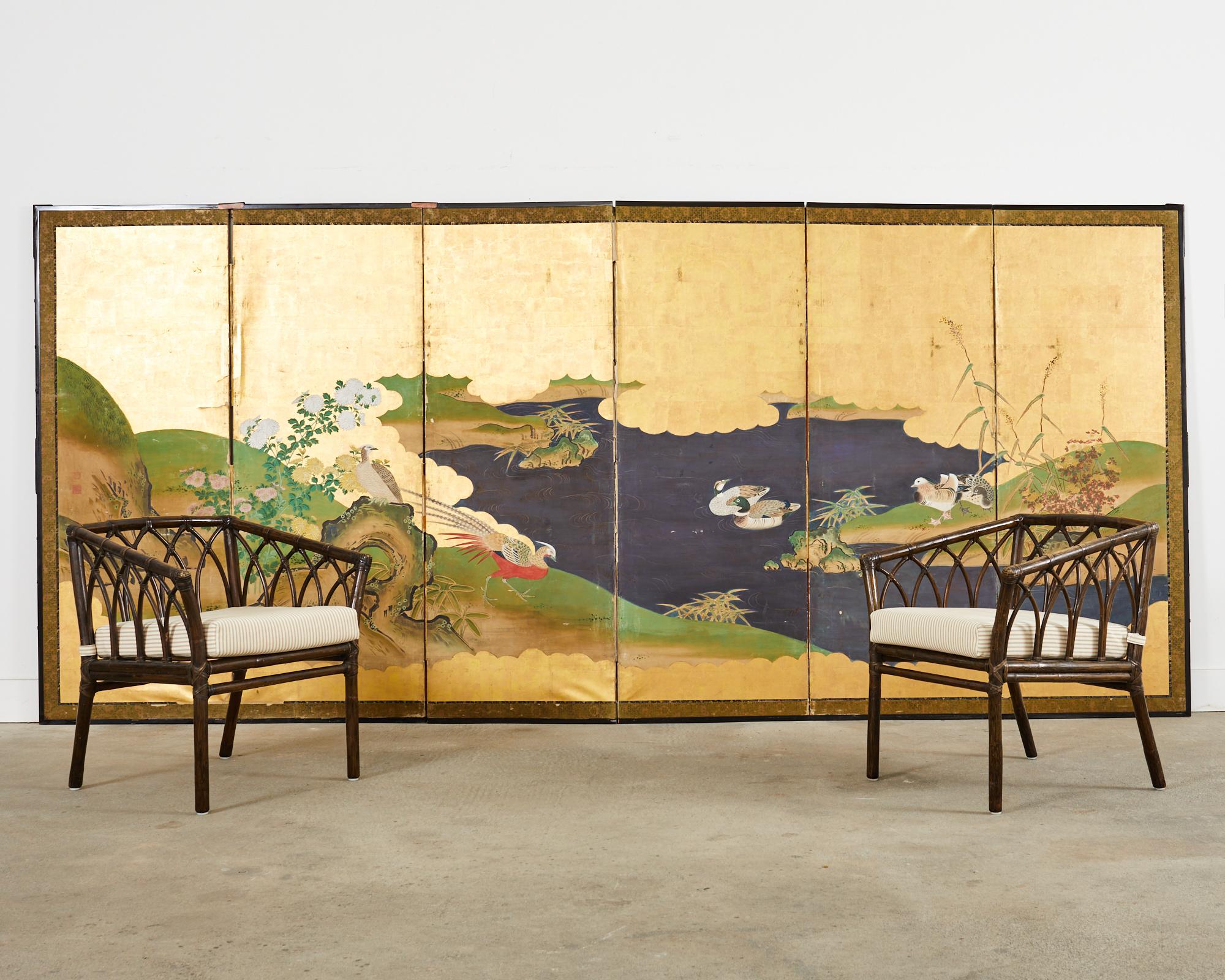 Stunning late 19th century Japanese Meiji period six panel byobu screen featuring a deep blue waterscape with pheasants and ducks. Made in the Kano school style with natural ink and color pigments over a dramatic gold leaf square ground. The