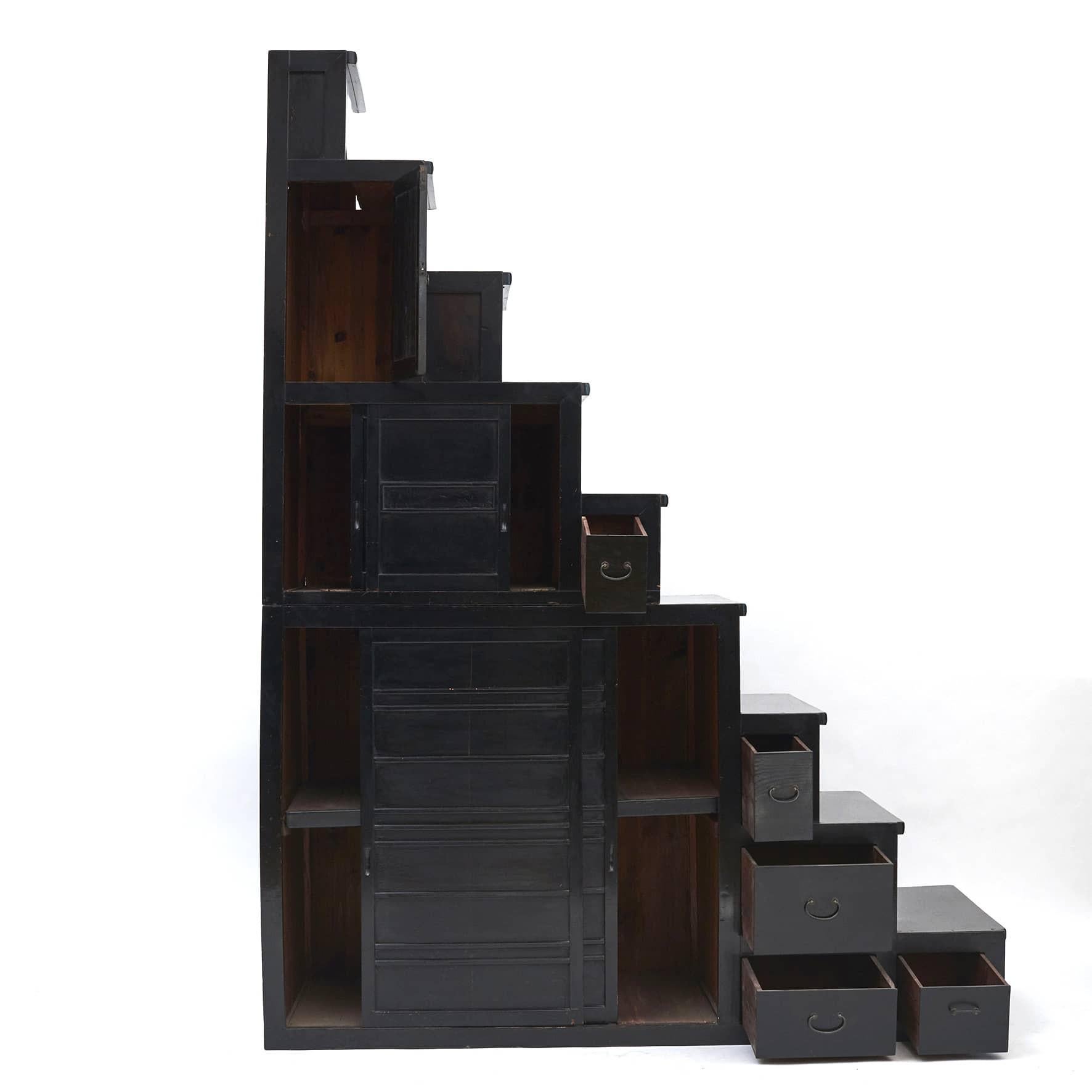 A Japanese staircase Tansu cabinet from the Meiji period.
Crafted from pine and elm wood with black lacquer.

This very large staircase Tansu is in two parts ( 104 cm + 128 cm) and features convenient stepped storage capacity with sliding doors