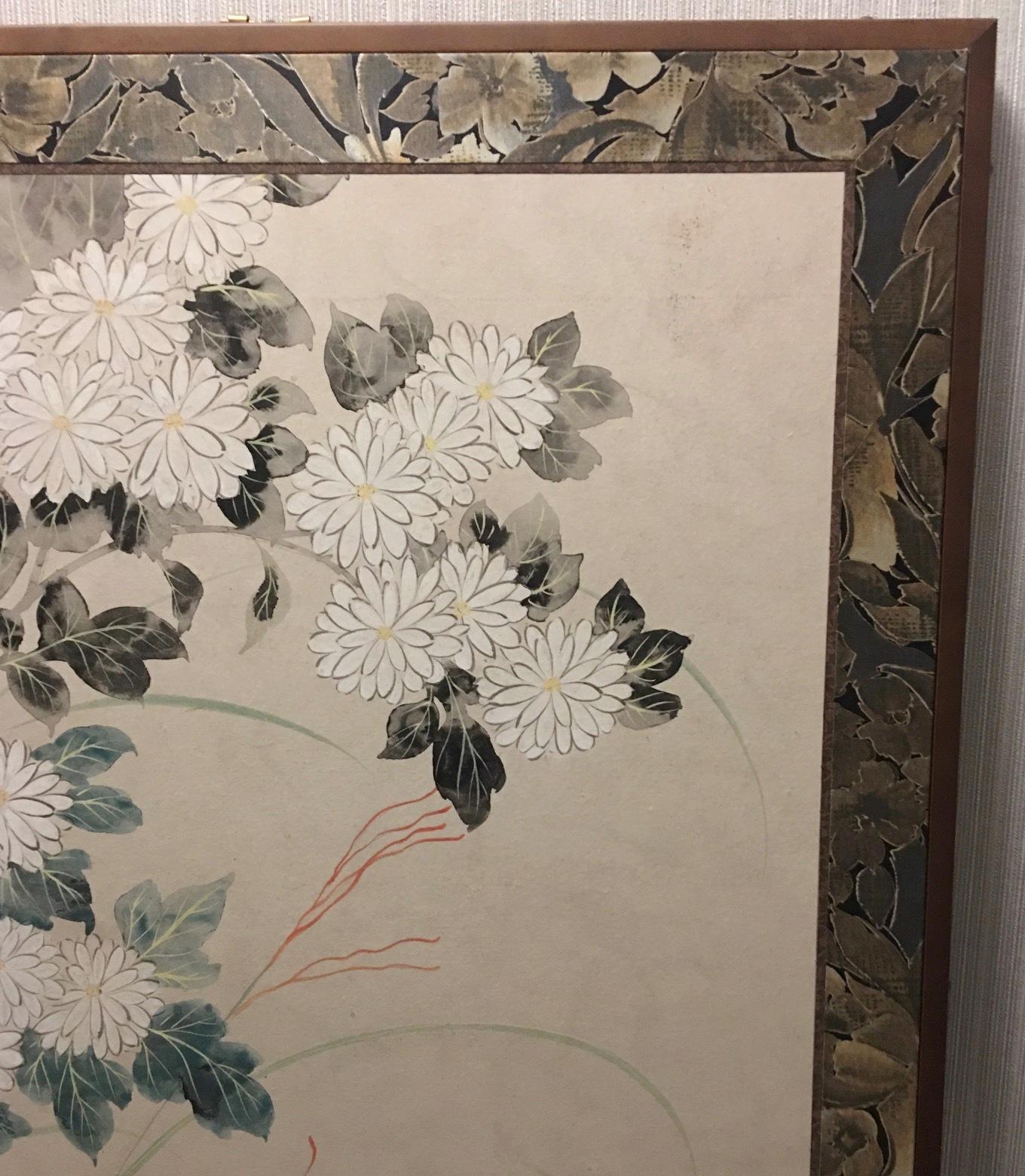Japanese Meiji/Taisho period two panel folding screen richly painted on Mulberry paper and depicting chrysanthemums and morning glories on a ivory background. The piece is framed by fine brocade and mounted on a black lacquered frame. Made in Japan