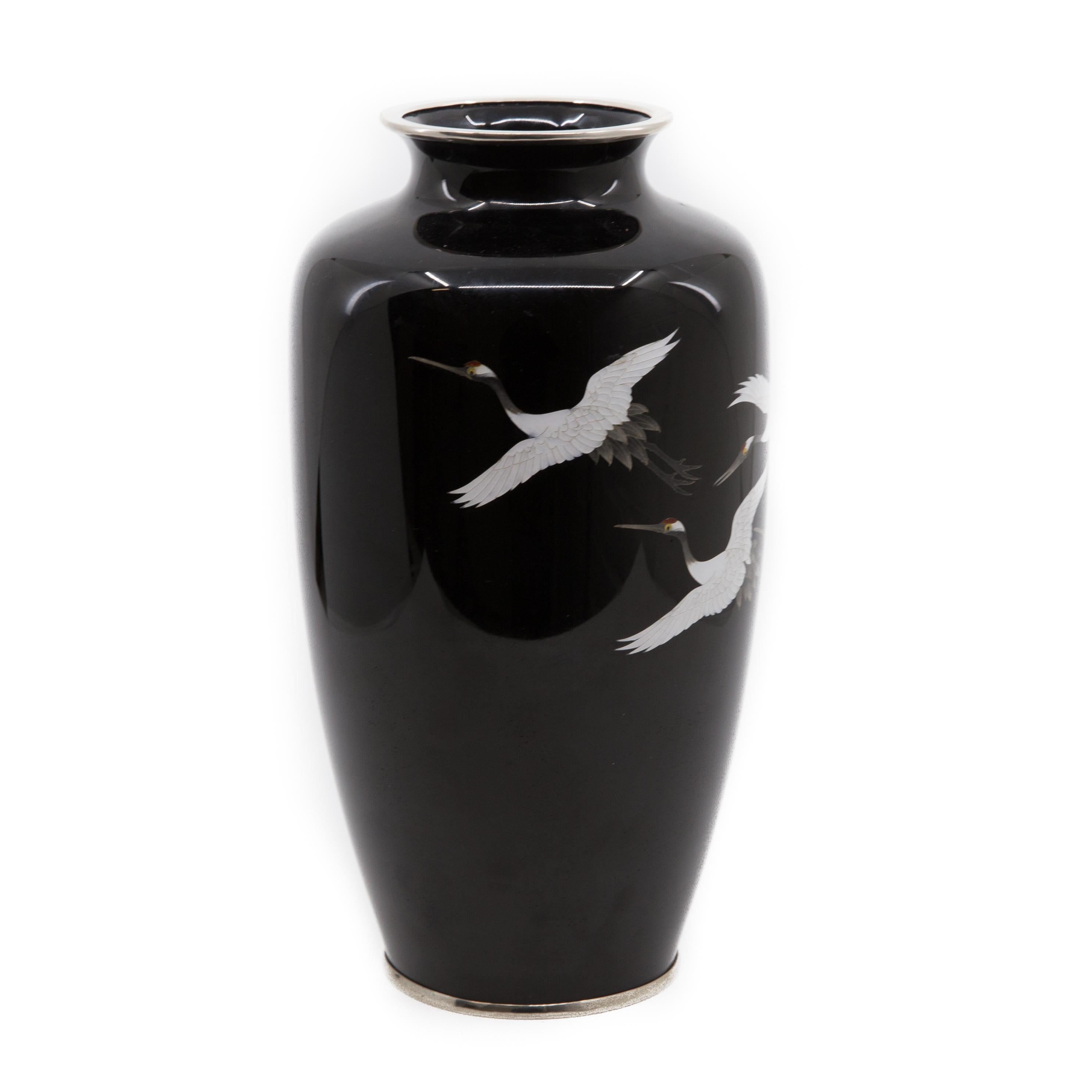 Offered is a vintage midcentury Japanese cloisonné enamel baluster form vase decorated with flying white cranes. The enamel work is in good condition with some scrape and wear evident on the metal base. The vase stands approximately 10” in height.