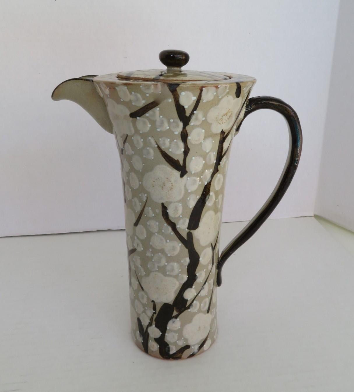 REDUCED FROM $325...Exquisite Mid-Century Modern Japanese tall and slender ceramic pitcher with top.  Decorated with stylized cherry blossom branches, with white flowers on a gray green background. Lovely form.  Very Good condition with minor wear