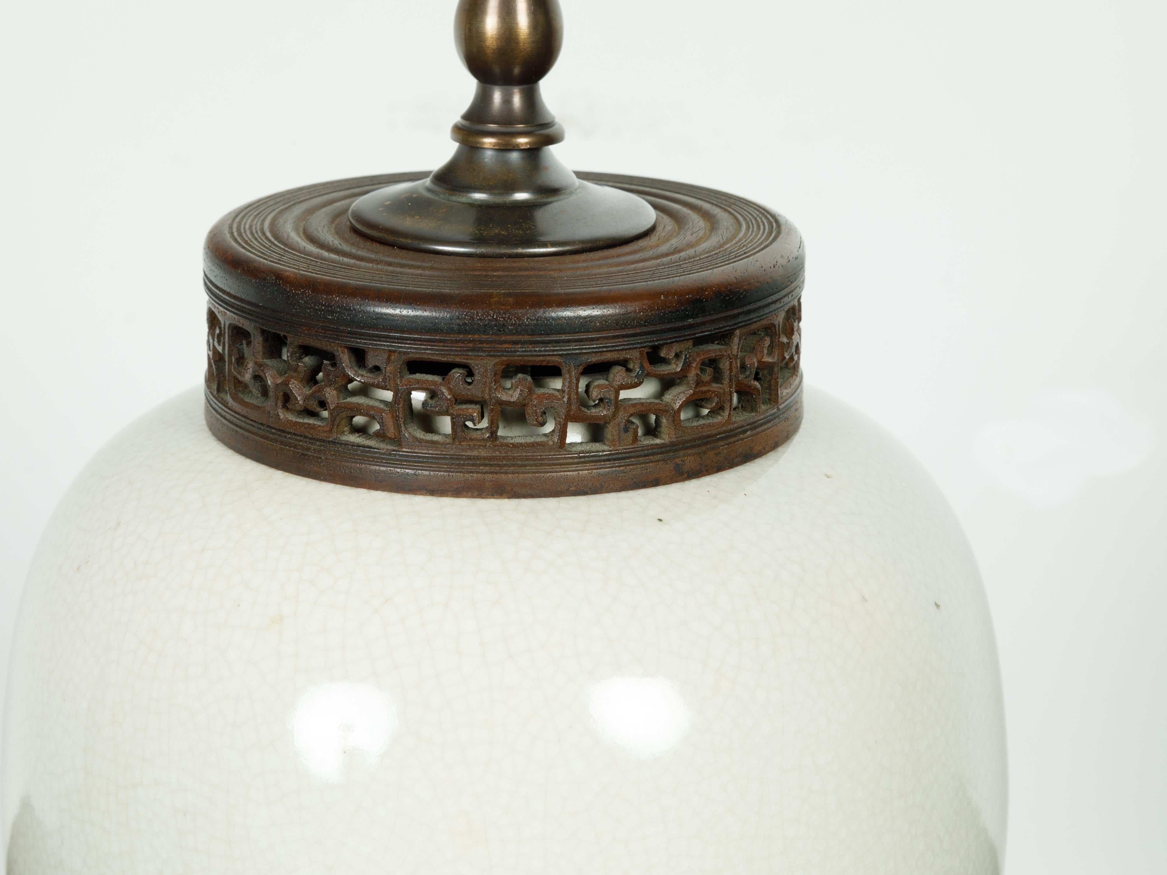 Lampe de table vintage japonaise du milieu du 20e siècle, avec finition craquelée et base en lucite. Créée au Japon au milieu du siècle dernier, cette lampe de table présente un vase en céramique blanche au glaçage craquelé, surmonté d'un anneau