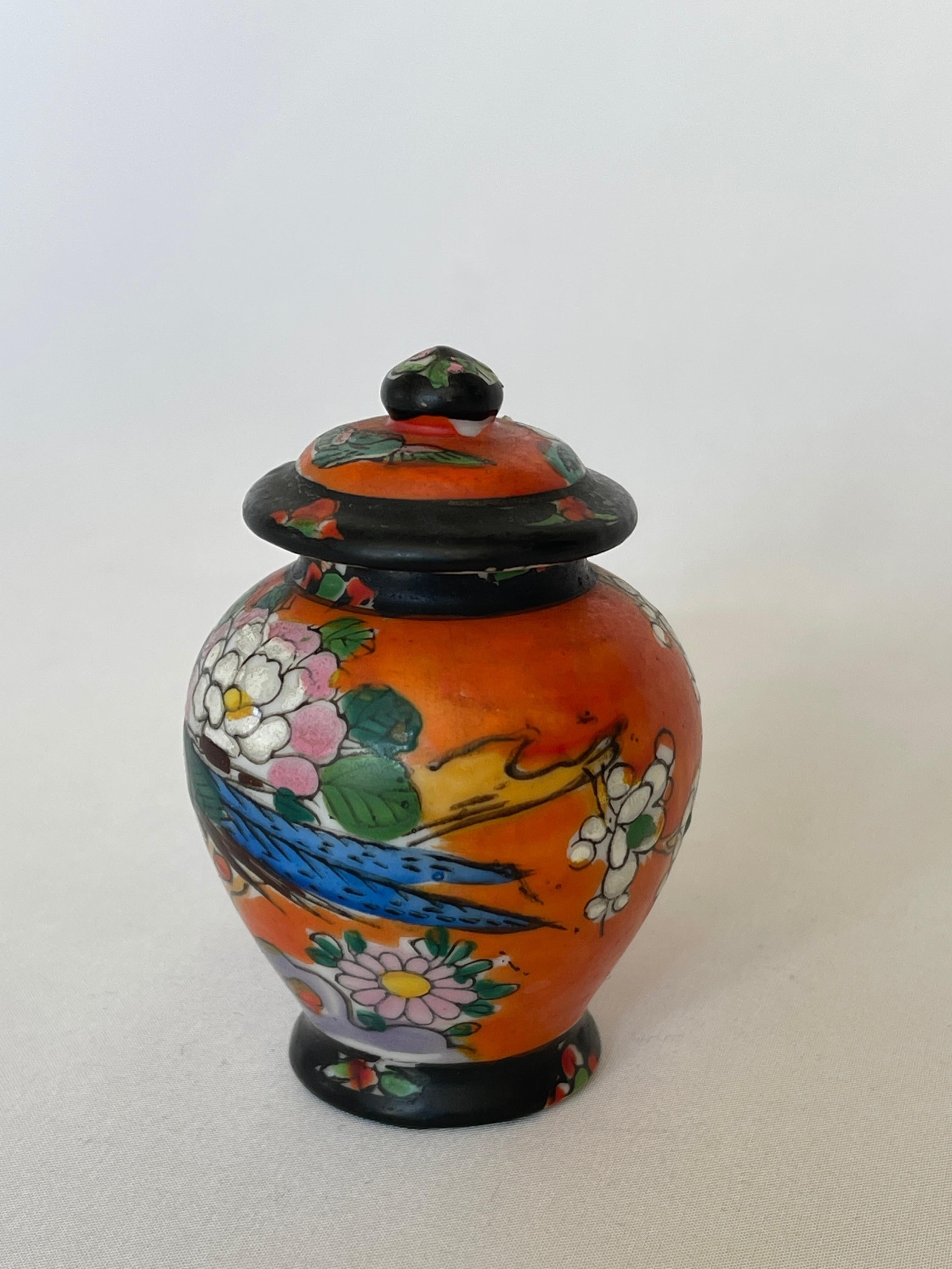 Hand painted Japanese porcelain miniature ginger jar with handled top.
Old Japan motifs of a peacock with chrysanthemum flower, dogwood trees, clouds and and butterfly. 

Stamped with signature on bottom, T & T Made in Japan Hand paint.