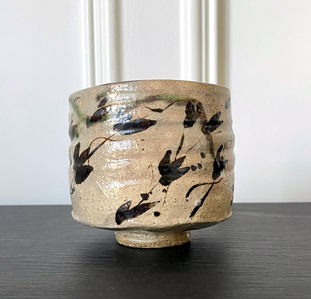 A Japanese Kutsu-gata (clog-shaped) chawan (tea bowl) circa 19th century possibly older. The stoneware bowl potted from buff clay has a slight irregular shape and an unusual depth for a tea bowl. Of Mino ware Oribe type, the chawan was entirely
