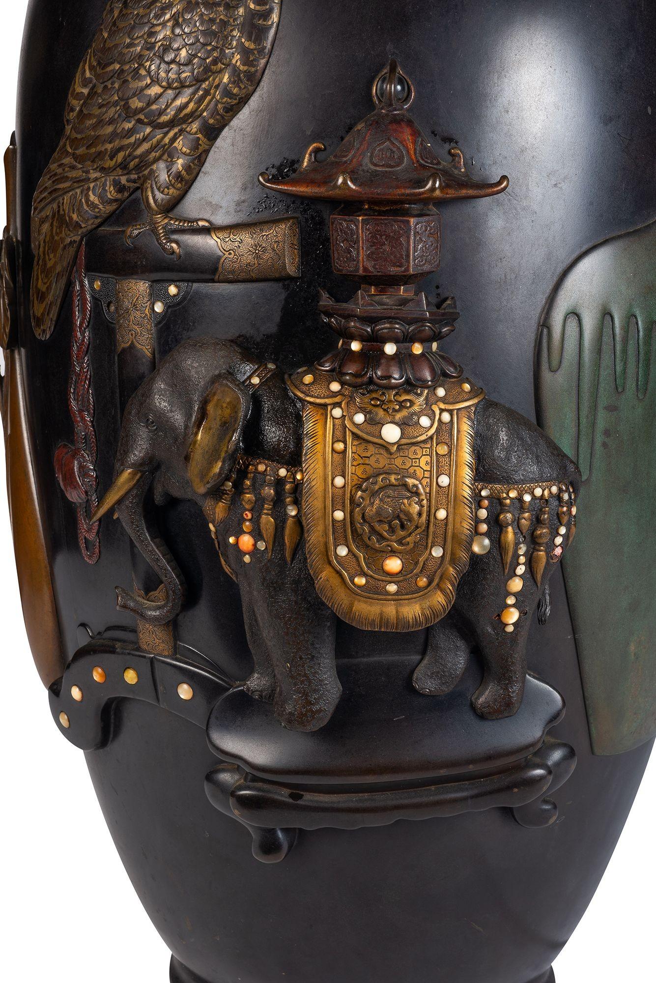 Eine wunderbar dekorative japanische Vase aus der Meiji-Zeit (1868-1912) aus patinierter Bronze und Mischmetall. Dargestellt sind ein Gebetsvogel auf einer Sitzstange, ein Elefant mit vergoldetem Sattel, der einen Pagodenwagen trägt, sowie