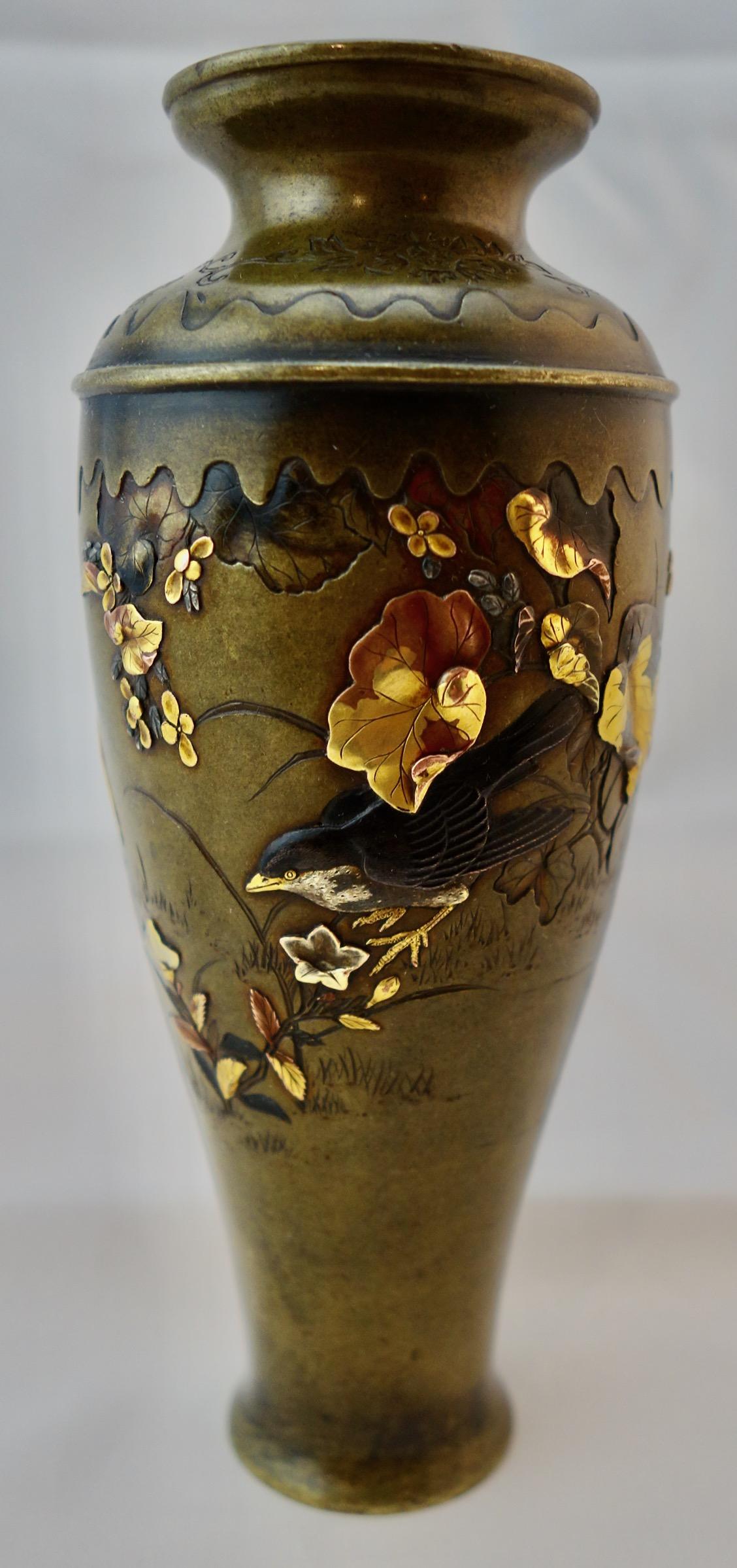 Japanese mixed metal shakudo vase depicting birds fishing among rich foliage. The vase is 5 1/4