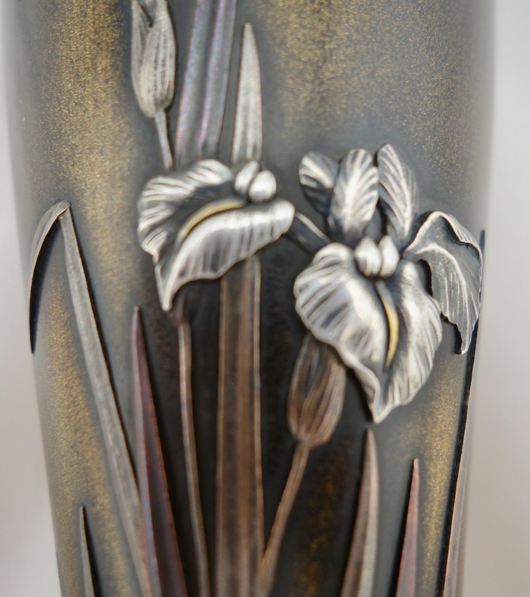 Vase shakudo japonais en métal mixte de la période Meiji. Le vase représente des fleurs d'iris argentées sur une base en bronze. Signé sur le côté par le fabricant, et marqué sur le fond pour l'atelier Nogawa. Le vase présente une légère perte de