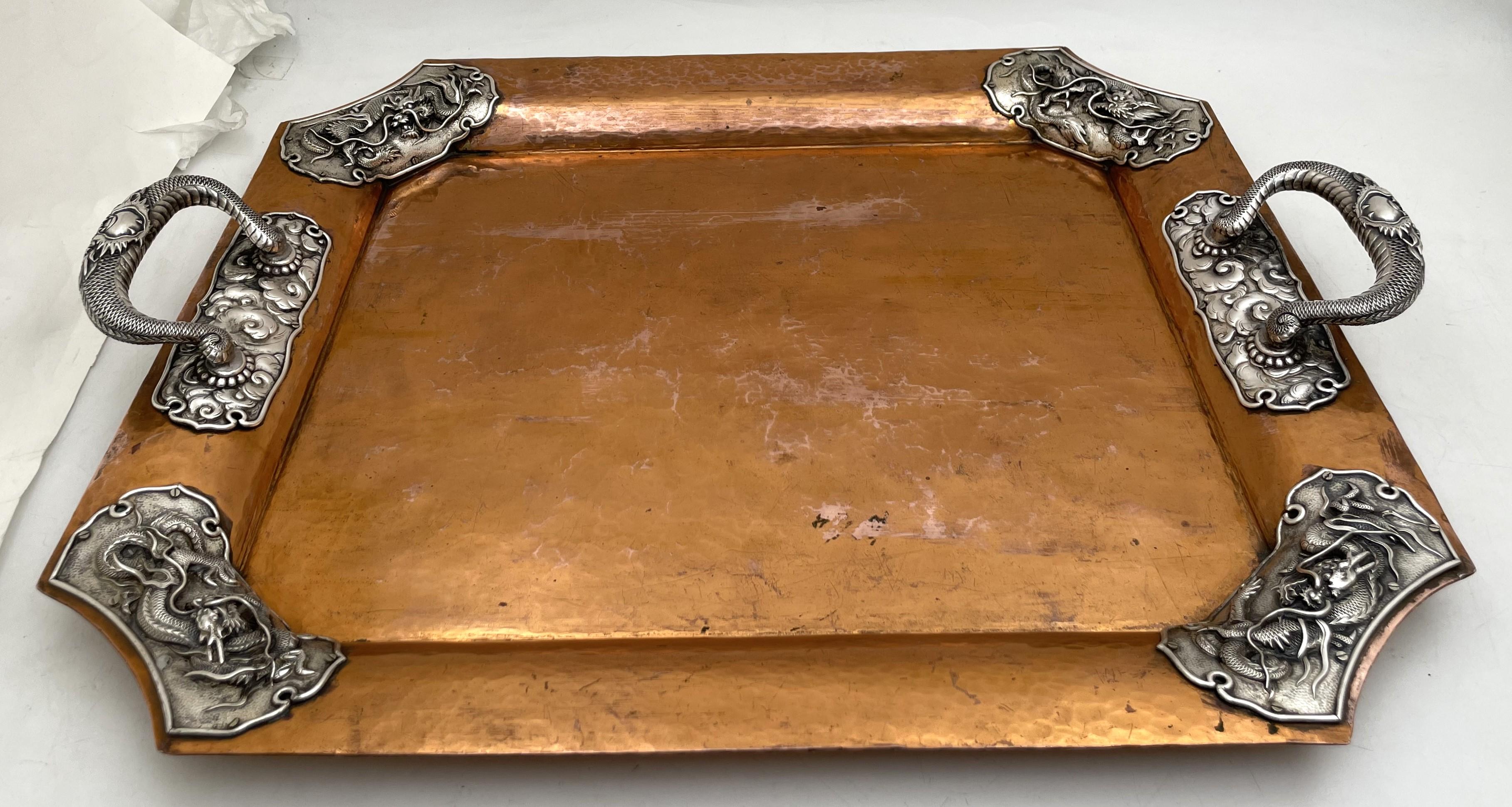 Japanese mixed metal copper and silver two-handled tray, from the late 19th or early 20th century, beautifully adorned with dragon motifs in relief on the rim and handles. It measures 20 1/2'' from handle to handle (inner length is 18 1/2'') by 16''
