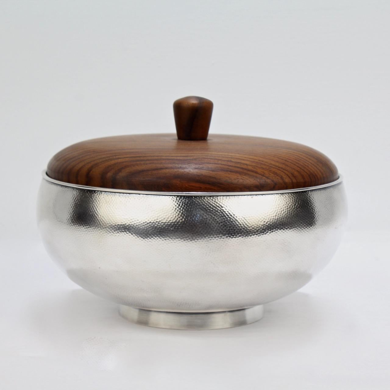 A very fine hand hammered sterling silver bowl with a wooden lid by Asahi Shoten.

The silver body with stippled hammer marks throughout and the interior with a liver sulfur finish. The wooden lid has knob form finial.

The base is marked for Asahi