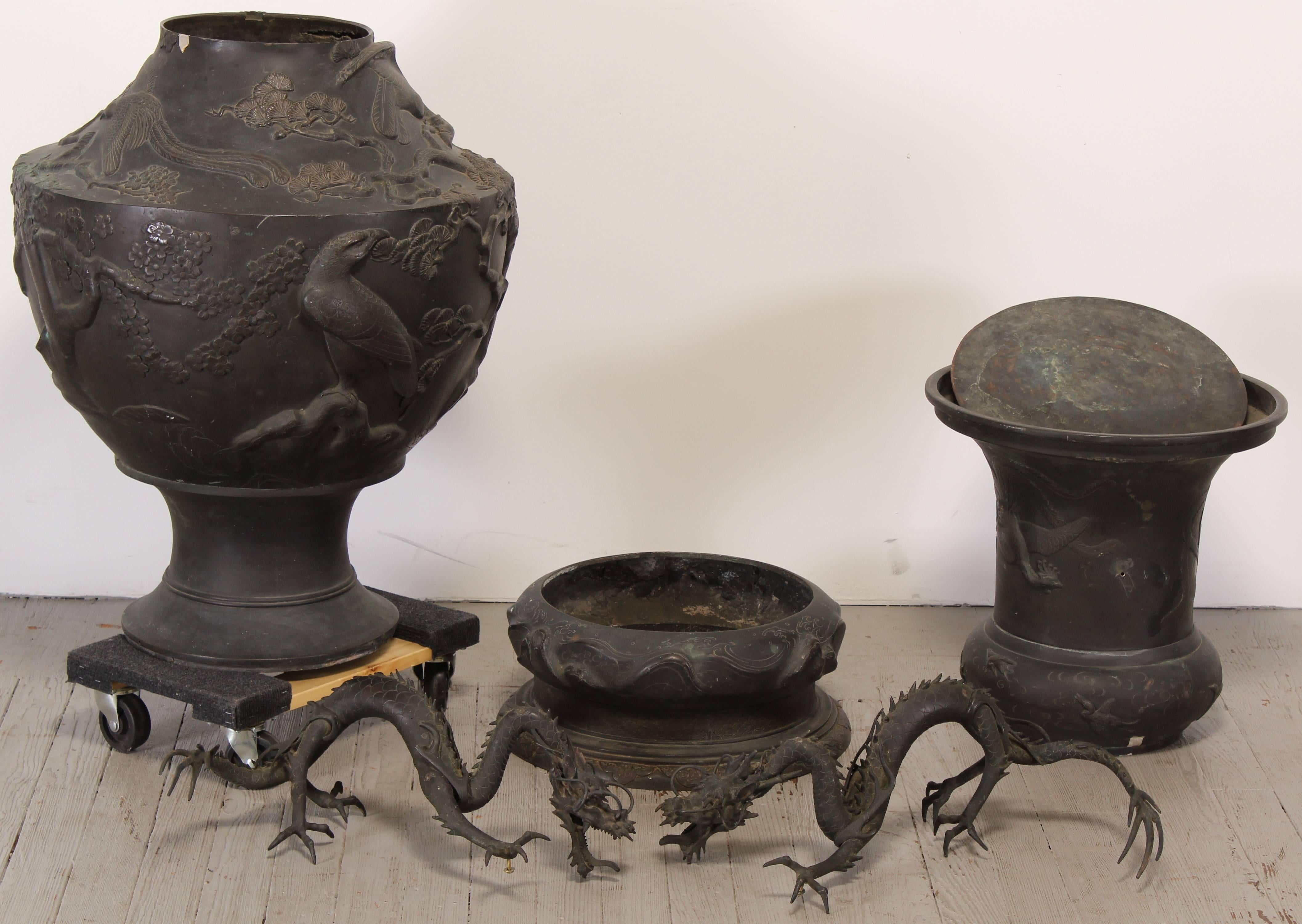 Jarrón monumental japonés de bronce con dos grandes asas de dragón. Parece que hay tres aves diferentes grabadas en relieve en la superficie: pavo real, águila y grullas. Data del periodo Meiji. Ha habido reparaciones recientes en los pasadores que