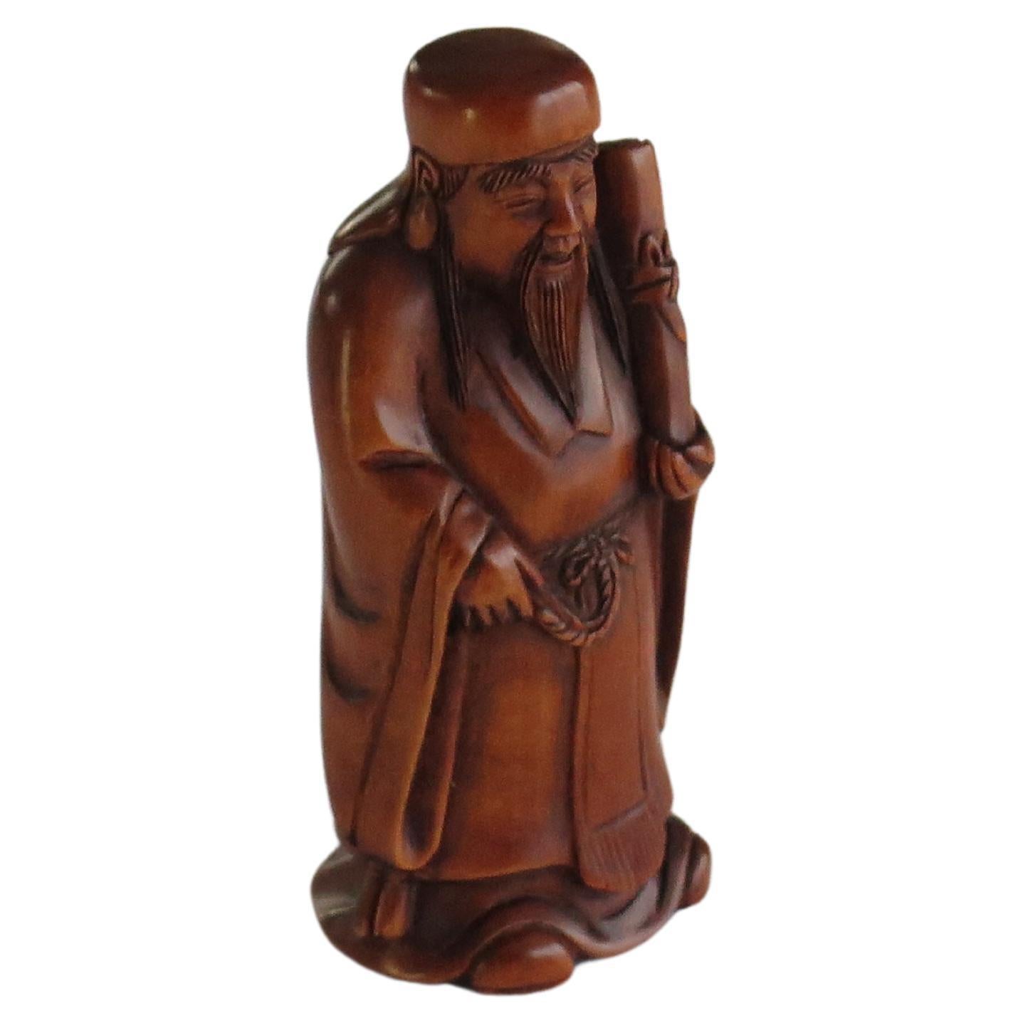 This is a boxwood Netsuke, modelled as a Sage, probably Chinese, which we attribute to a Japanese maker, circa 1920.

This piece is of good quality and very well carved showing a Chinese sage or immortal holding a scroll. The carving is very