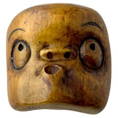 Netsuke japonés de Hyottoko, representada a través de una máscara en la obra Noh como una idiota