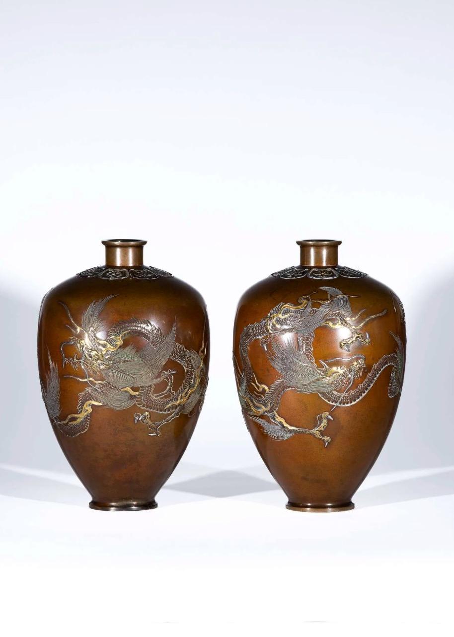 Pair of patinated bronze teardrop vases with pair of flying Ryu dragons facing each other, fully carved and with inlays and applications in silver, copper gold, and bronze.

At the top below the neck symbols and geometric patterns enclosed within
