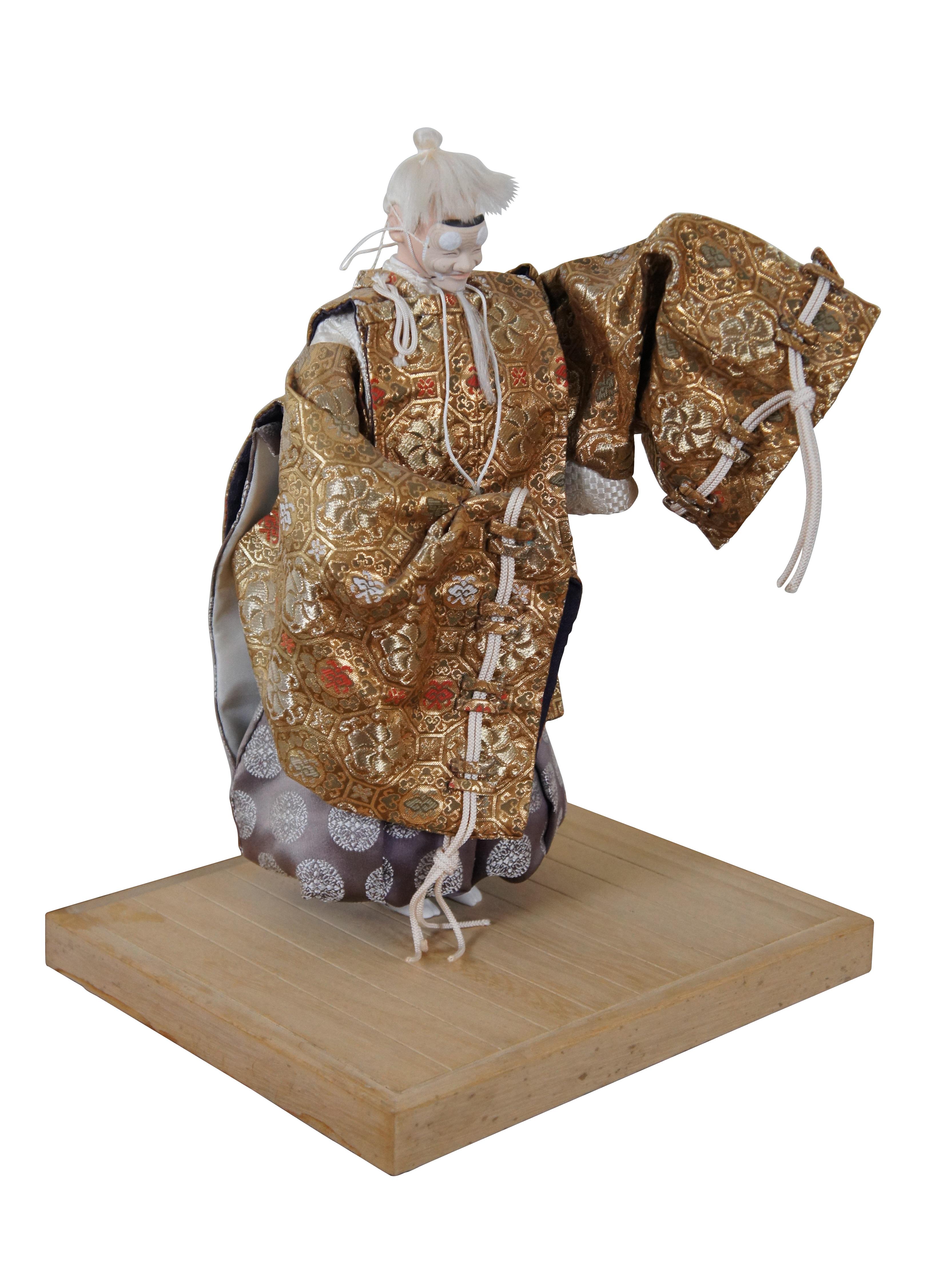 Vintage decorative doll / figurine depicting an old man / diety character from Japanese Noh Theatre. The mask appears to be a Hakushiki-jo / Okina style with benign expression, the suggestion of a movable jaw, long beard, and pom pom shaped