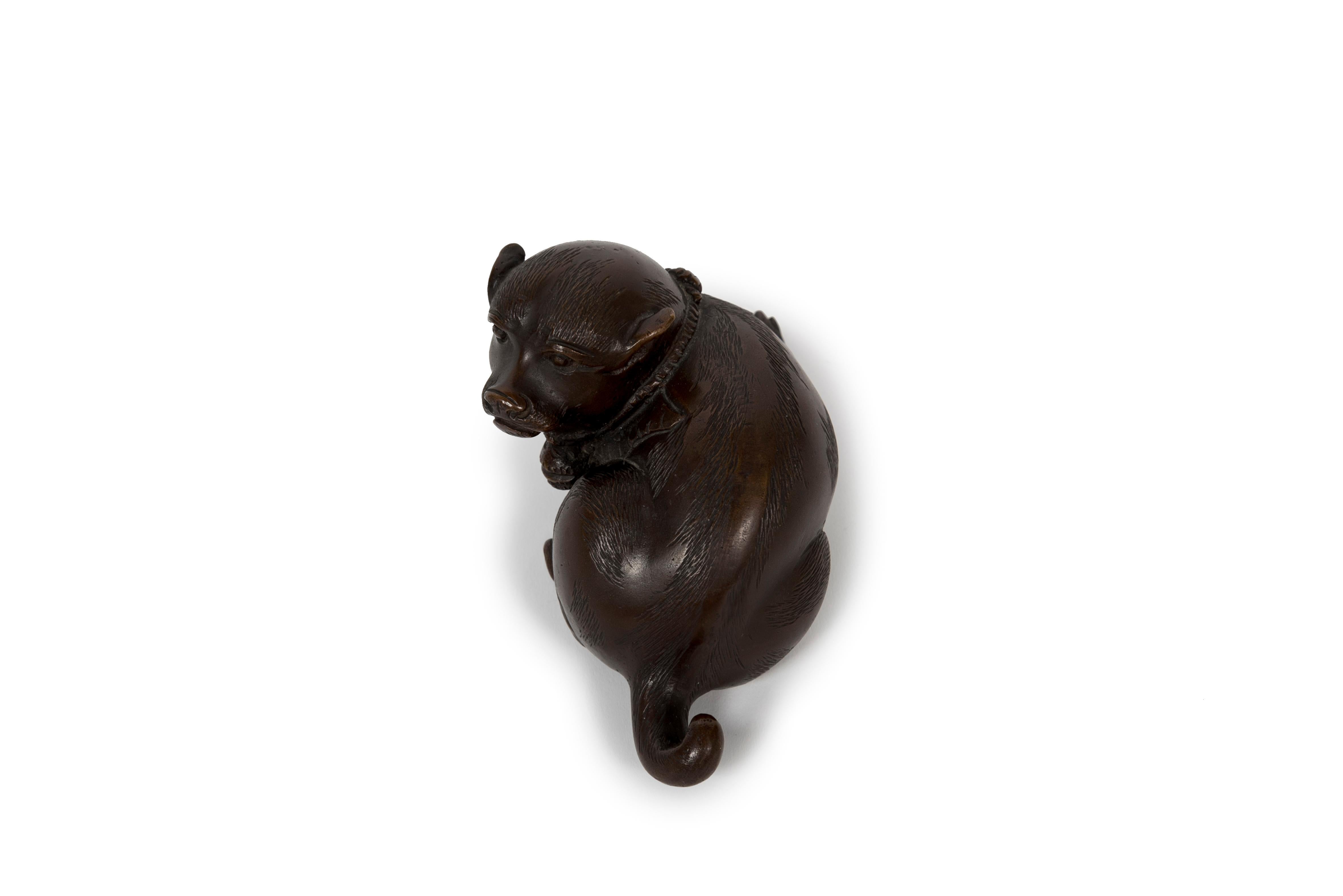 Bronze okimono sculpture with a deep brown patina, of a lying puppy, probably of shiba inu breed, represented with its head facing its rear. This kind of subject is common in traditional Nippon sculptures, this specific piece reminds of archaic