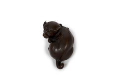 Japanese okimono sculpture of a lying puppy with its head facing its rear
