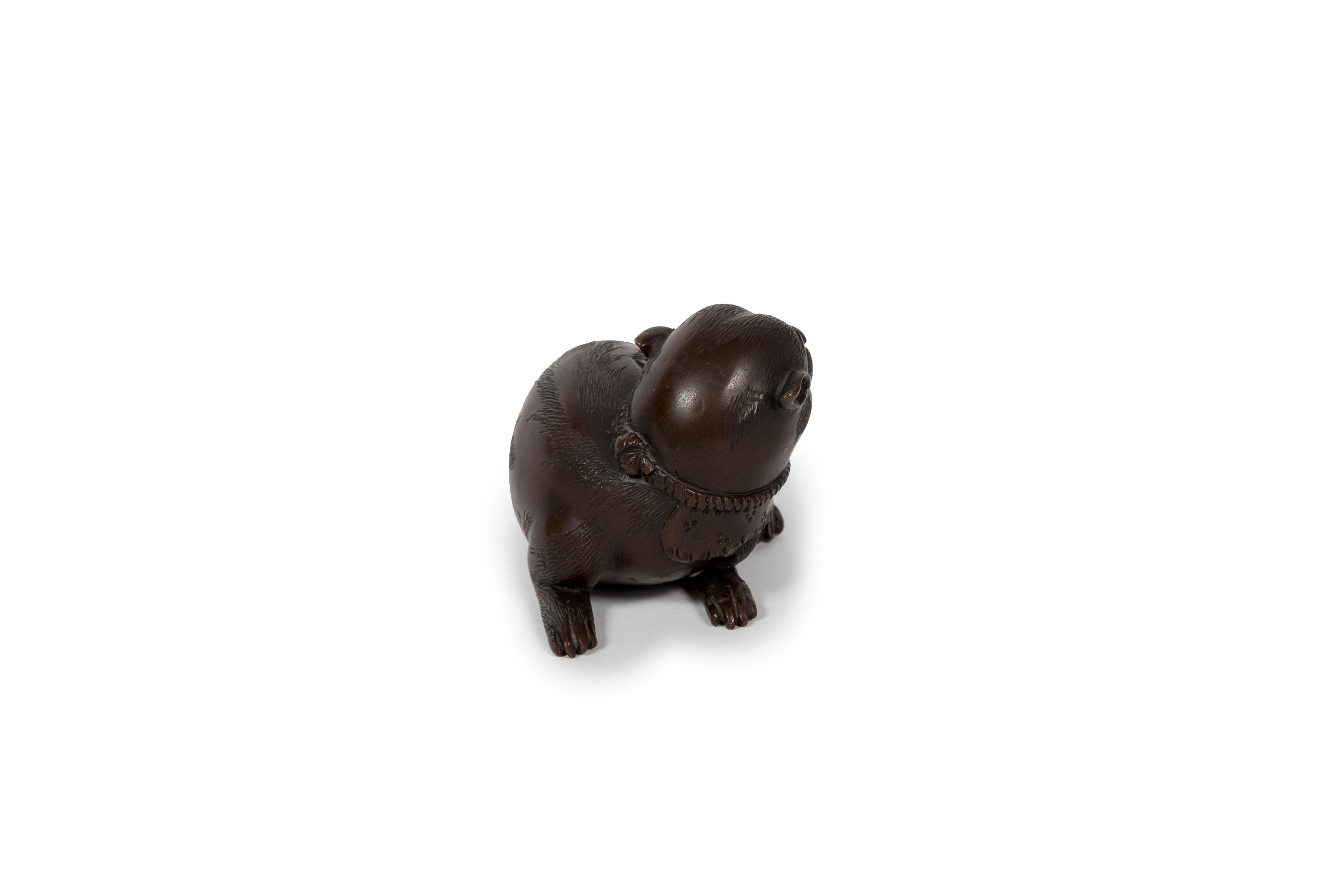 Cast Japanese okimono sculpture of a lying puppy with its head facing its rear For Sale