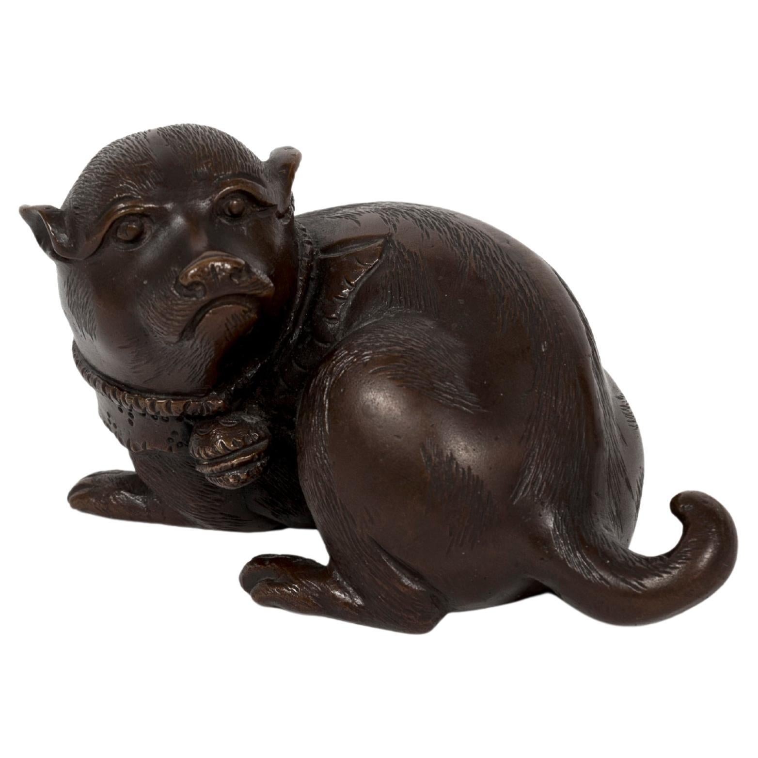 Escultura okimono japonesa de un cachorro tumbado con la cabeza hacia atrás