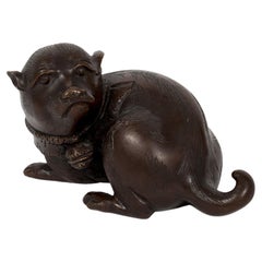 Escultura okimono japonesa de un cachorro tumbado con la cabeza hacia atrás