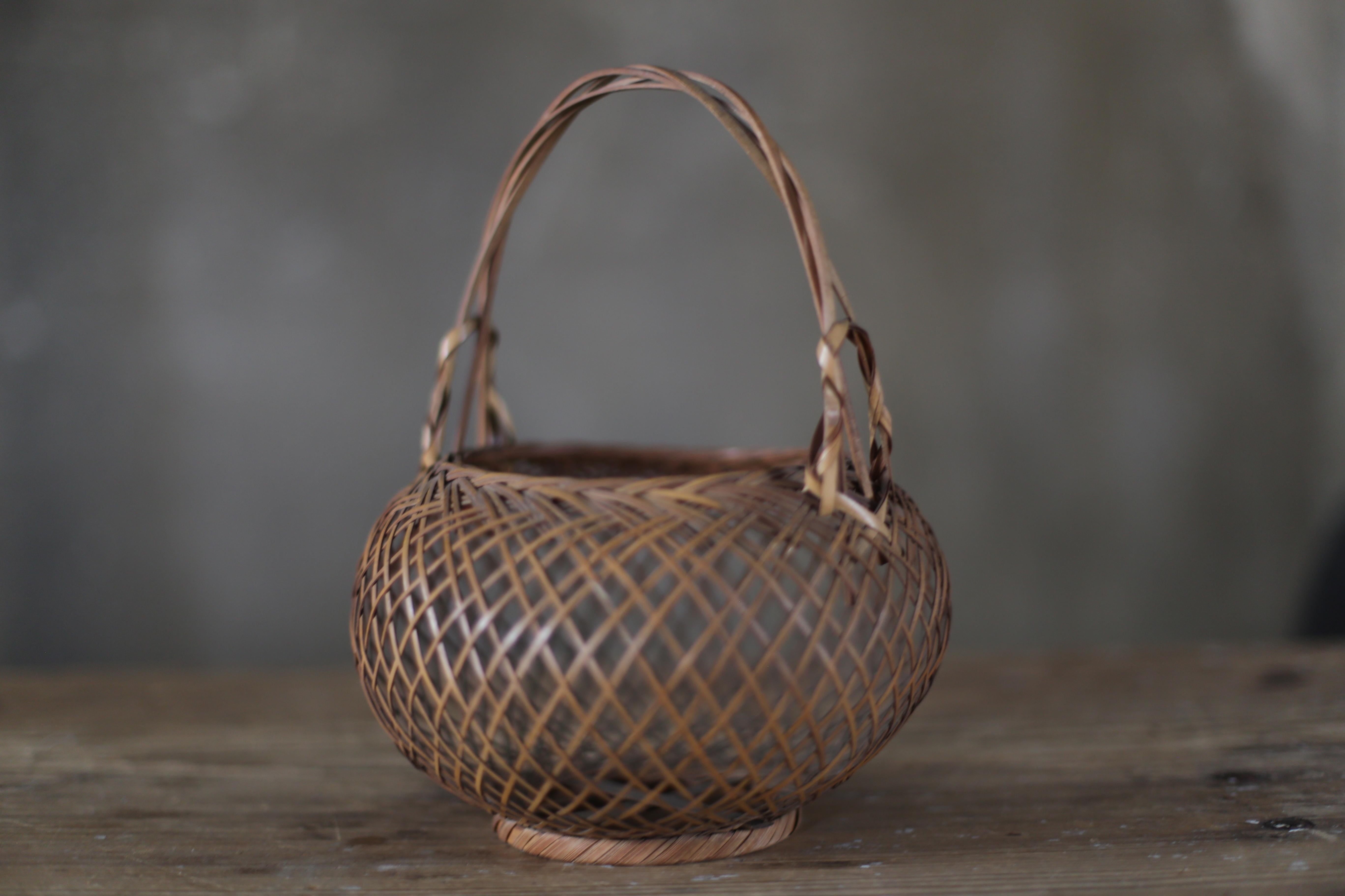 This is a woven bamboo basket made in Japan during the Meiji to Taisho eras (1868-1920).
It is a vase that imitates the shape.

It was hung on the wall or placed on a table to decorate with flowers.

Soot is attached and it is black like