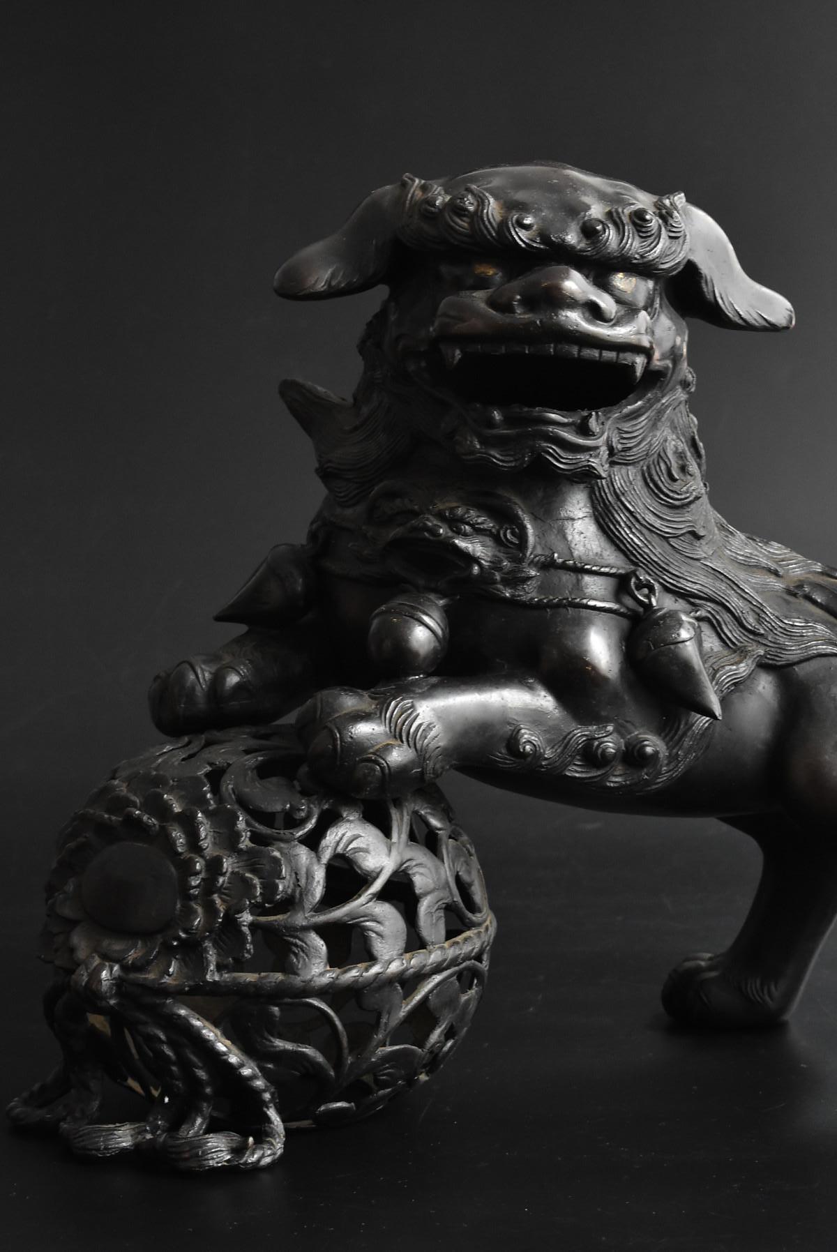 An old Japanese brass lion figurine.
It's big and very powerful.
The round thing at the foot of the lion is a peony.
It is a Temari with a peony pattern. (ball)

The lion symbolizes majestic strength, and the peony means gorgeous.
This