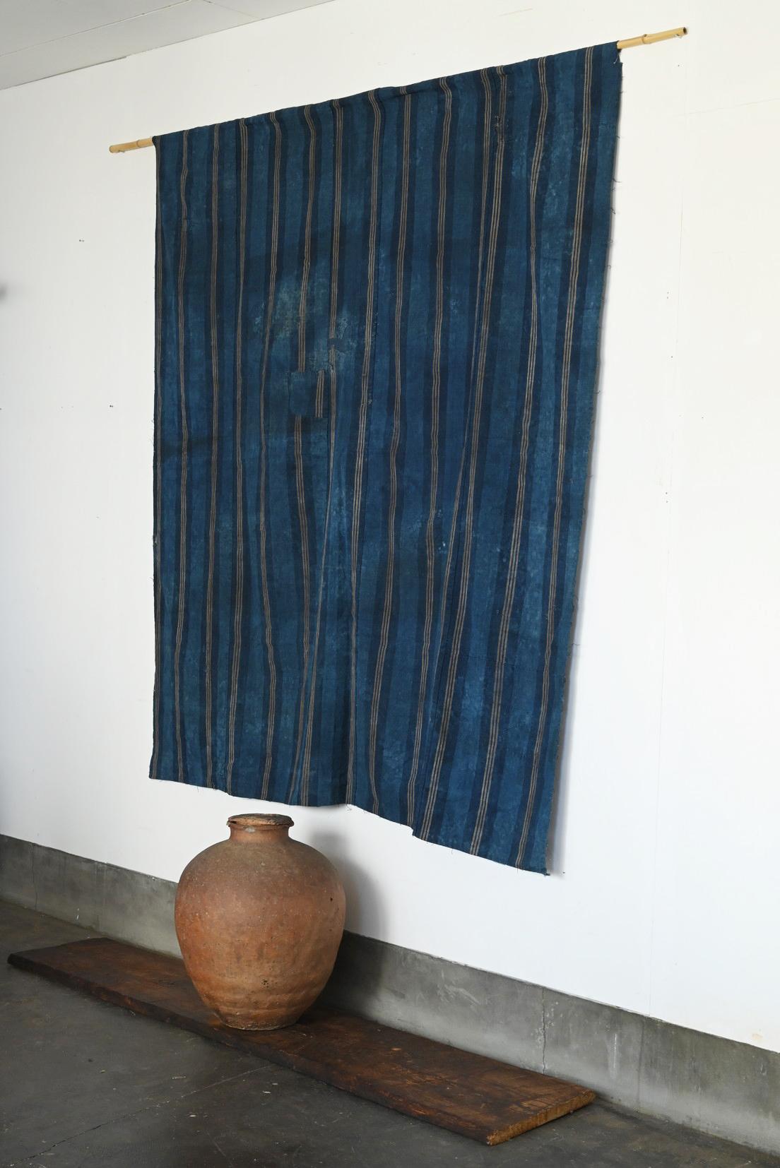 Il s'agit d'un ancien tissu japonais teint à l'indigo produit entre la fin de la période Meiji et la période Taisho. Trois fines lignes jaunâtres régulièrement espacées créent un rythme régulier sur un fond indigo profond. Les rayures verticales