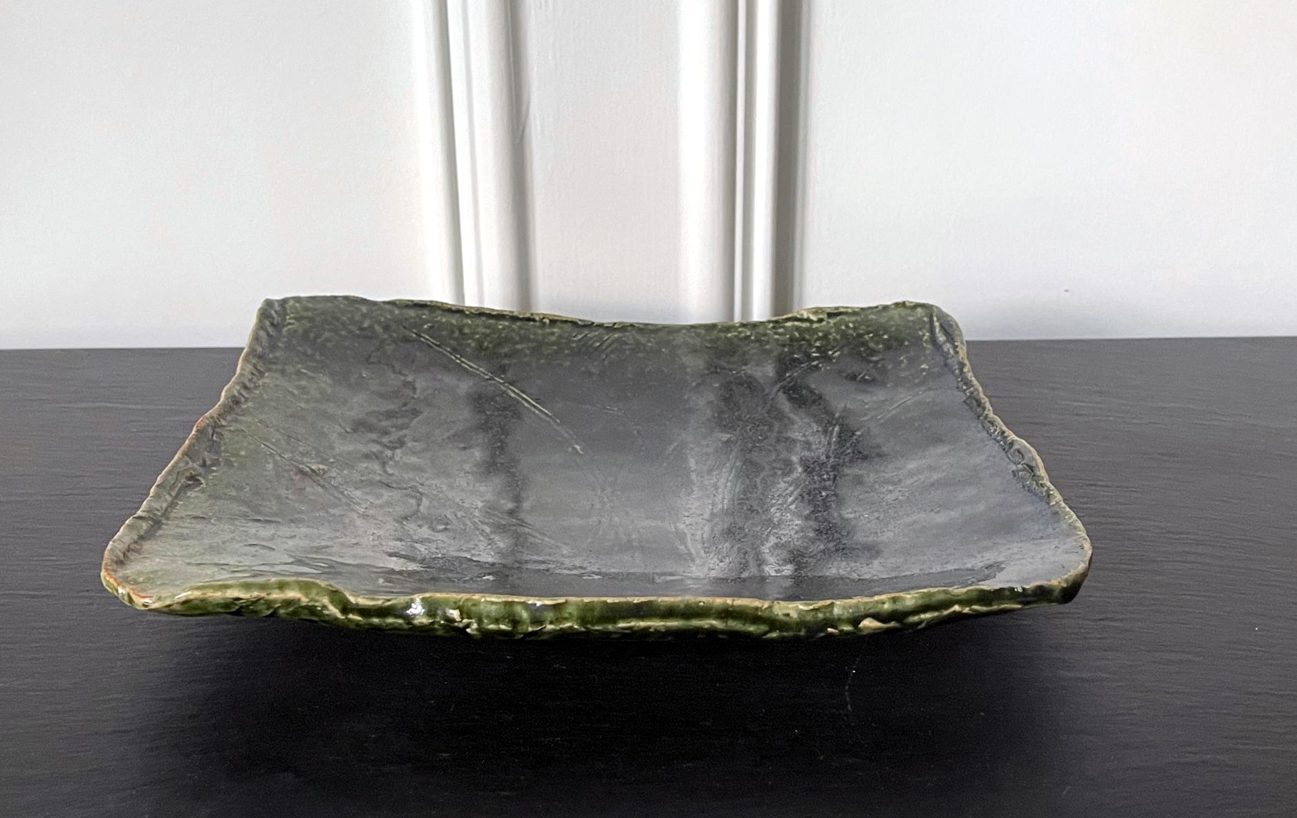 An Oribe-Style rectangular dish with a slightly concaved slab body and up-turned irregular edges, made by Kitaoji Rosanjin (1883-1959) circa 1930-50s. The surface of the stoneware was incised with a design of grass blades, possibly iris plants, and