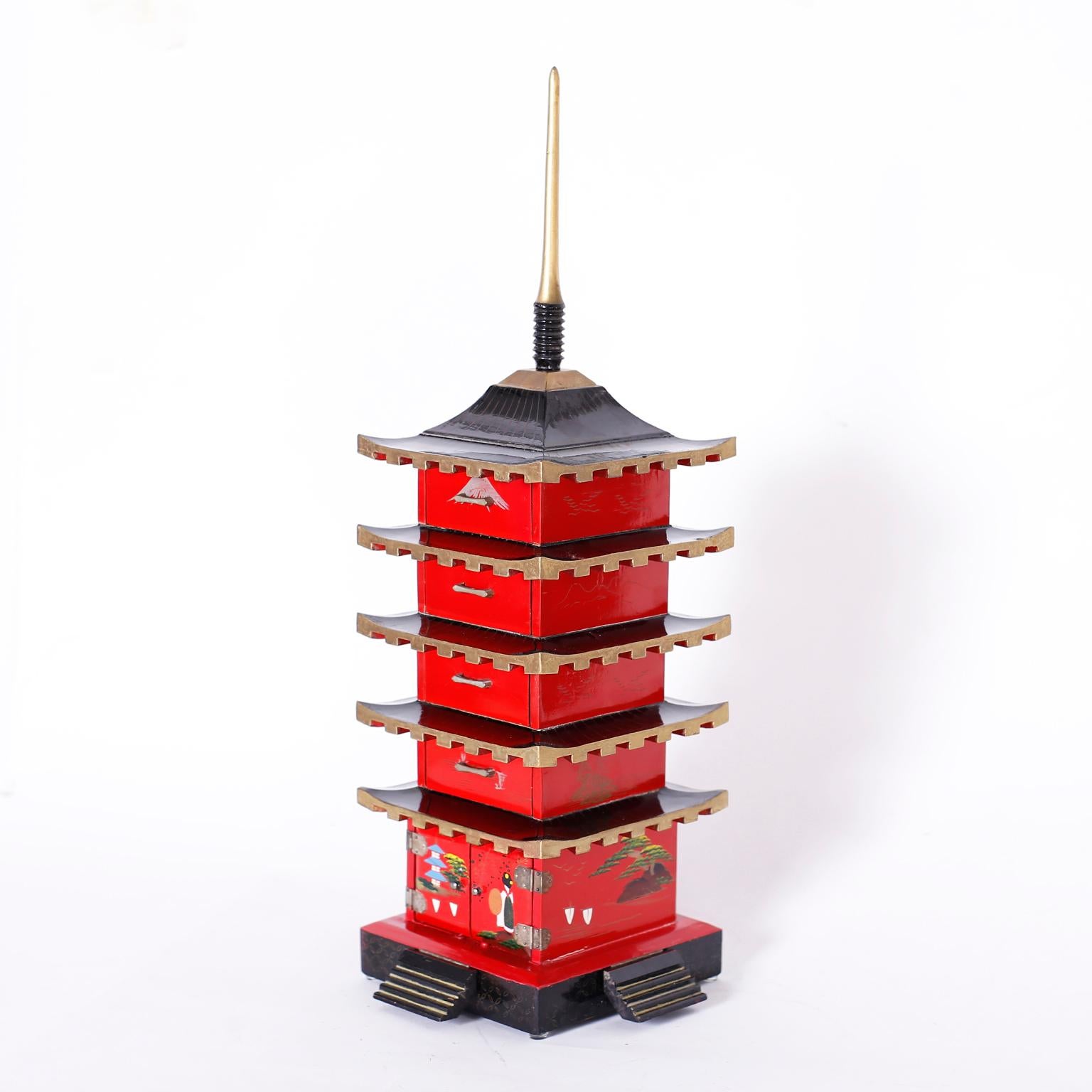 Japanese jewelry box constructed with wood in a pagoda or temple form with five drawers, lacquered in red and black, and decorated with stylized cultural lore.