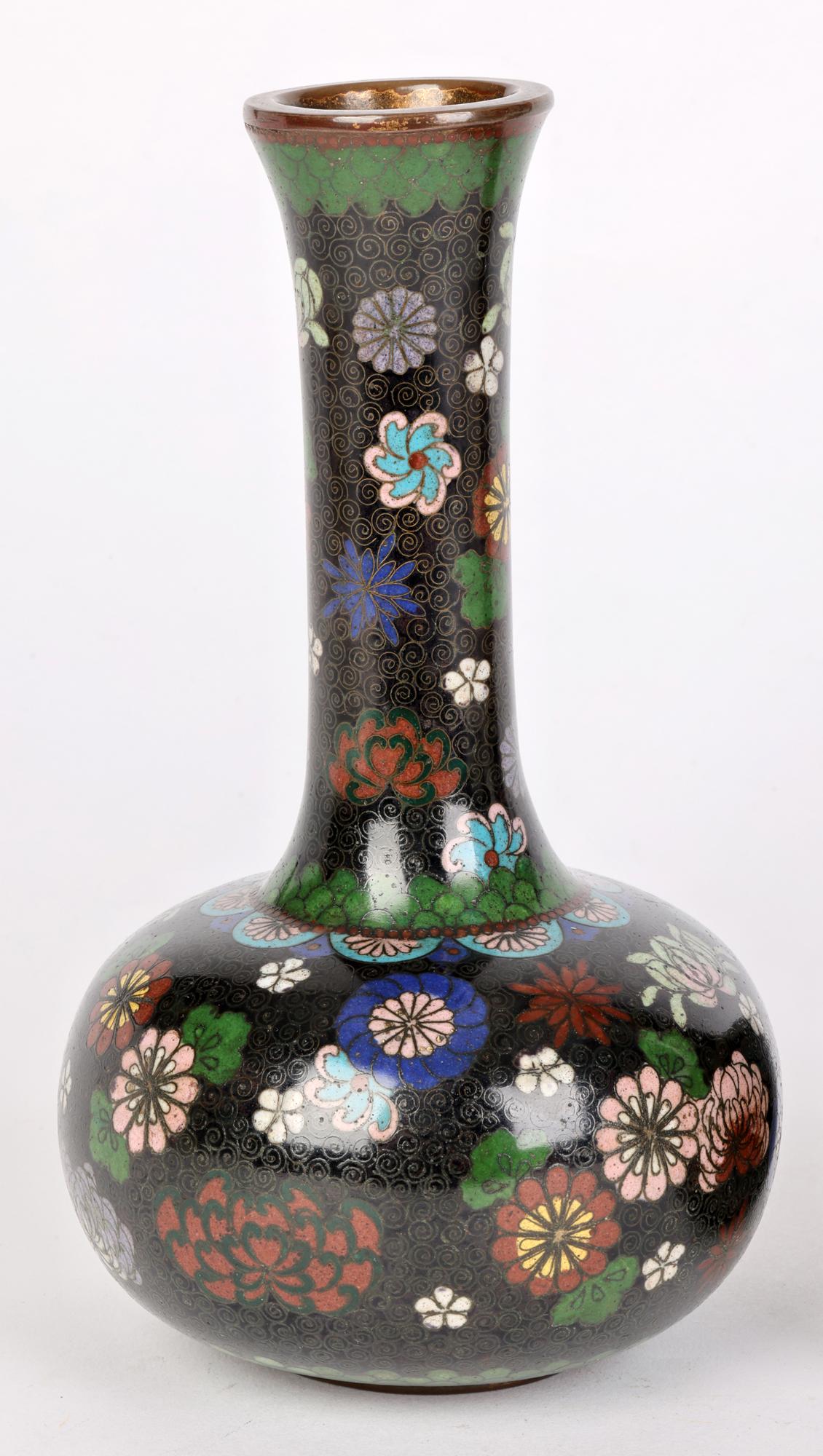 Fino par de jarrones japoneses con forma de botella de cloisonné del periodo Meiji, decorados con motivos florales dispersos y fechados entre 1868 y 1912. Los jarrones están ligeramente fabricados sobre una base metálica estrecha y plana, con un