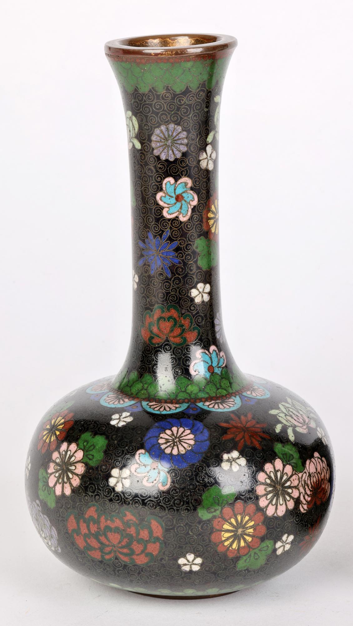 A fine pair Japanese Meiji period cloisonne bottle shaped vases decorated with scattered floral patterns and dating between 1868 and 1912. The vases are lightly made standing on a flat narrow metal base with a rounded bulbous shaped body and tall