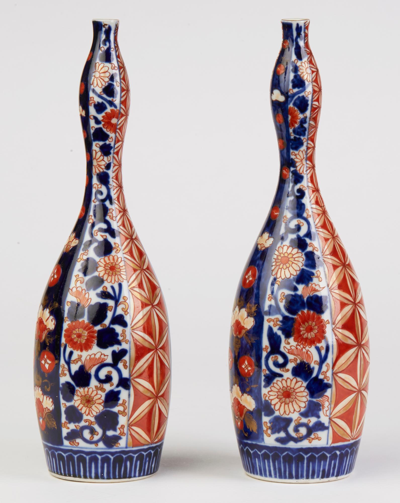 An unusual and stunning pair antique Japanese Meiji Imari Porcelain bottle vases of tall slender shape with a double gourd shaped neck dating from the 19th century. Both are decorated with vertical panels decorated with flowers and other typical