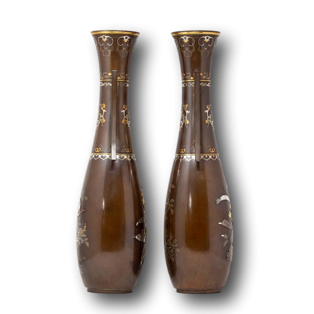 Intarsien aus Gold und Silber

Aus unserer japanischen Sammlung können wir Ihnen ein japanisches Paar Bronzevasen aus der Meiji-Periode anbieten. Die japanischen Bronzevasen in länglicher Form haben jeweils einen taillierten Hals, der von zwei sich
