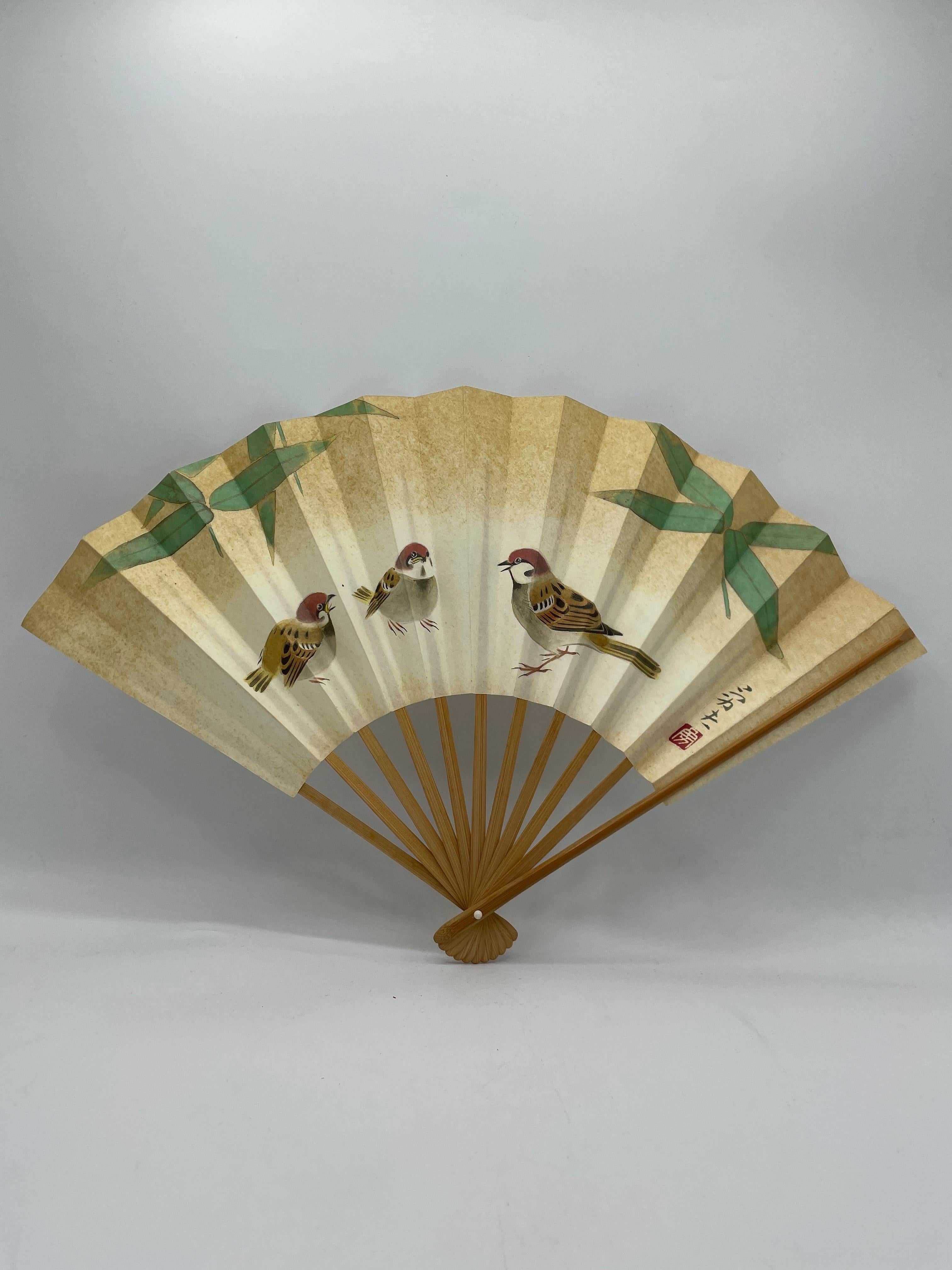 This is a fan which was made in Japan around 1990s in Heisei era.
This was a gift from the prefecture of Aichi on the September in 1988. 
This is made with a paper and bamboos. This fan is printed.
The design is three sparrows and some
