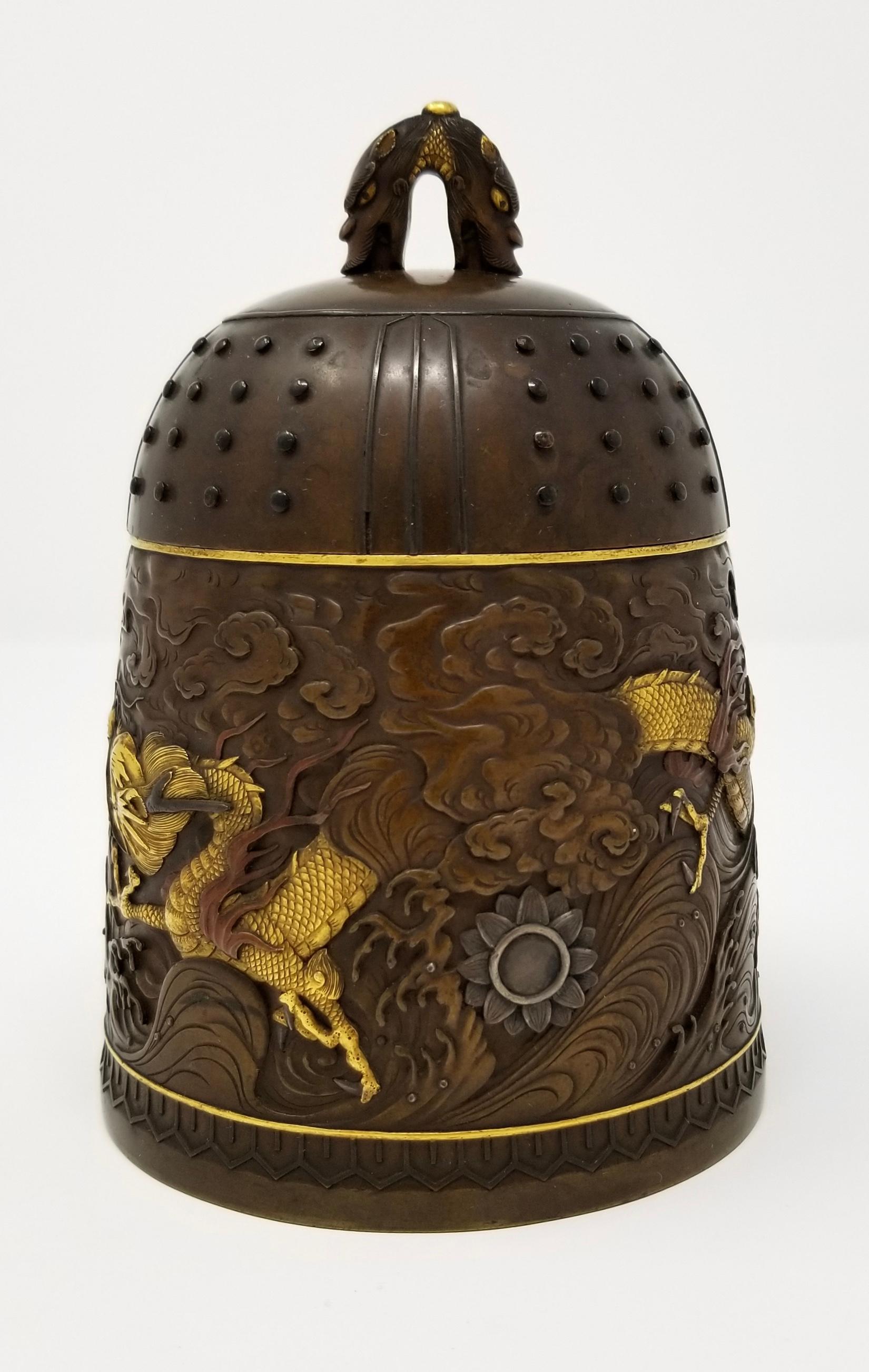 A marvelous Signed Japanese patinated bronze and mixed metal ‘Dragon’ bell-form box & cover from the Hattori Studio, signed, Meiji Period. The mid section of the Bell-Form box is meticulously decorated with a golden dragon flying throughout clouds