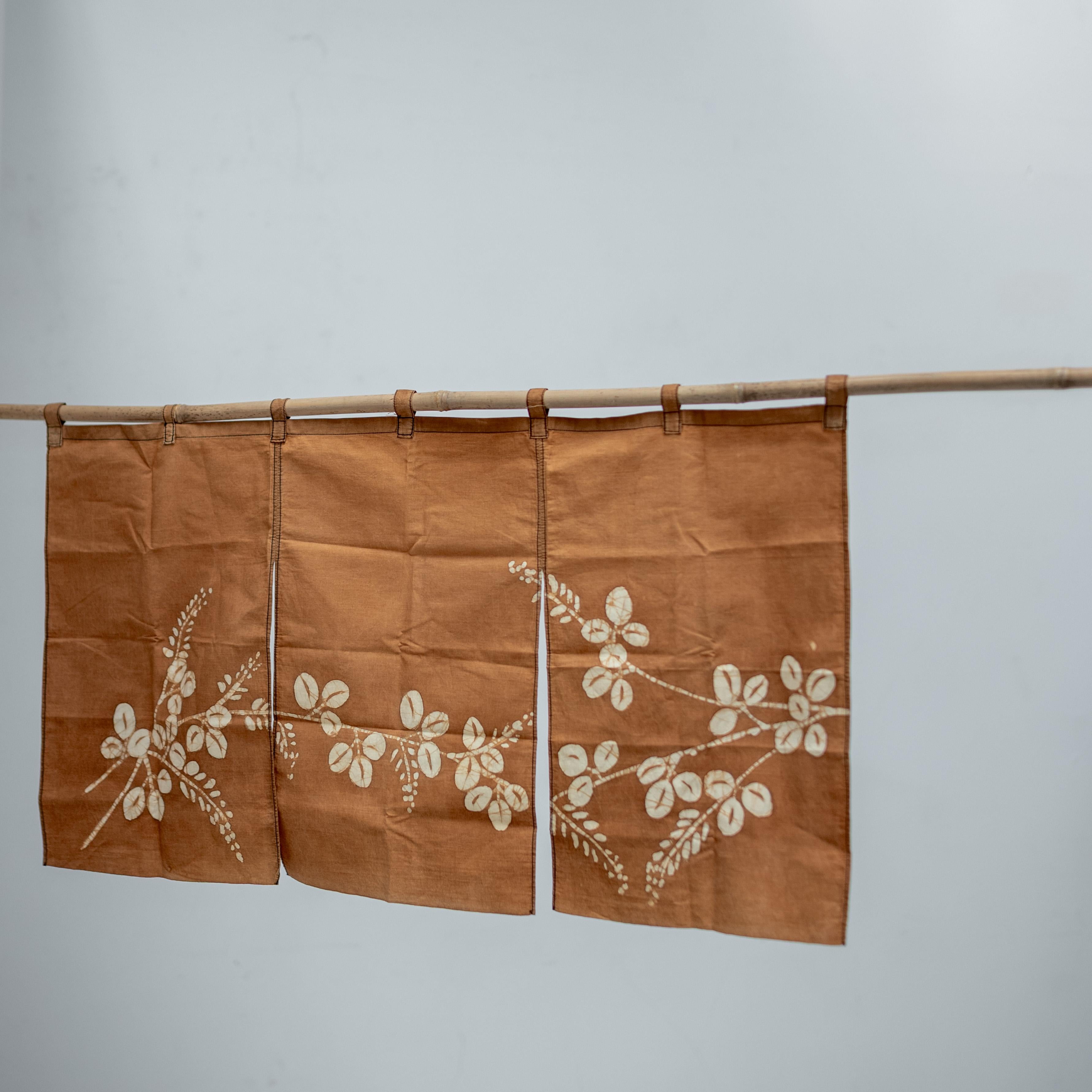 Charmant noren japonais de petite taille (diviseur de tissu traditionnel), teint à la main à l'aide de tanin de kaki naturel, datant de la période Taisho.  Cette pièce textile présente un délicat motif floral blanc teinté dans la masse qui s'étend