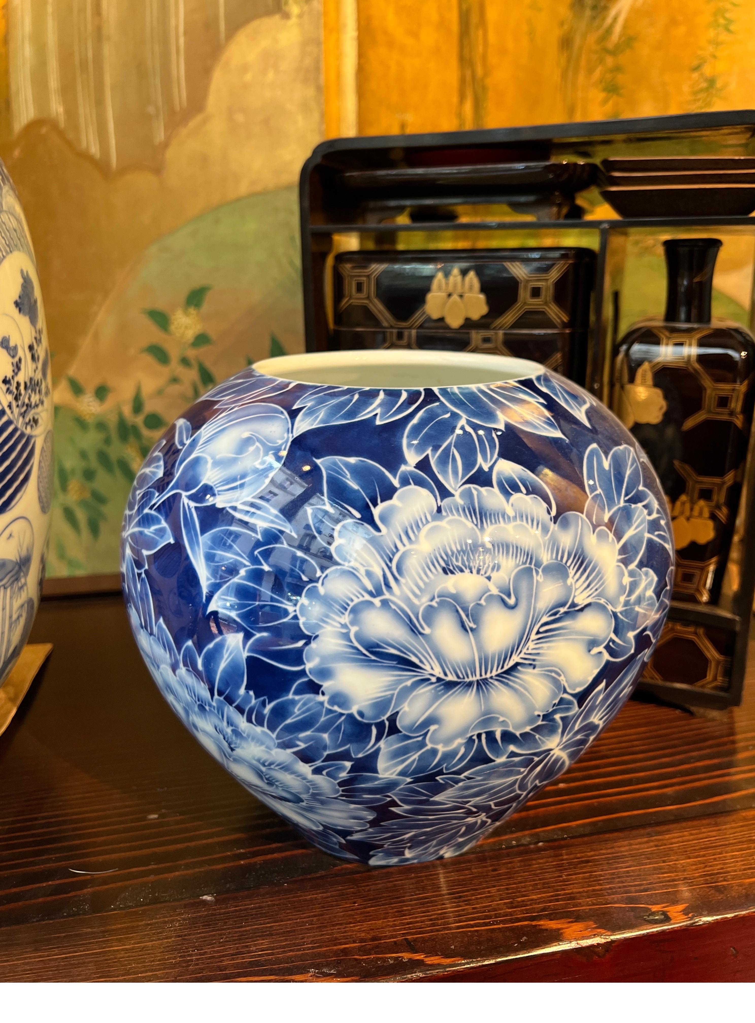 Eine atemberaubende japanische  Vase aus Porzellan in leuchtenden Blautönen, verziert mit  exquisite Pfingstrosenmotive.
 Diese kugelförmige Vase besticht durch ihre sorgfältige Handbemalung, die ihren Reiz als dekoratives Stück noch verstärkt.

