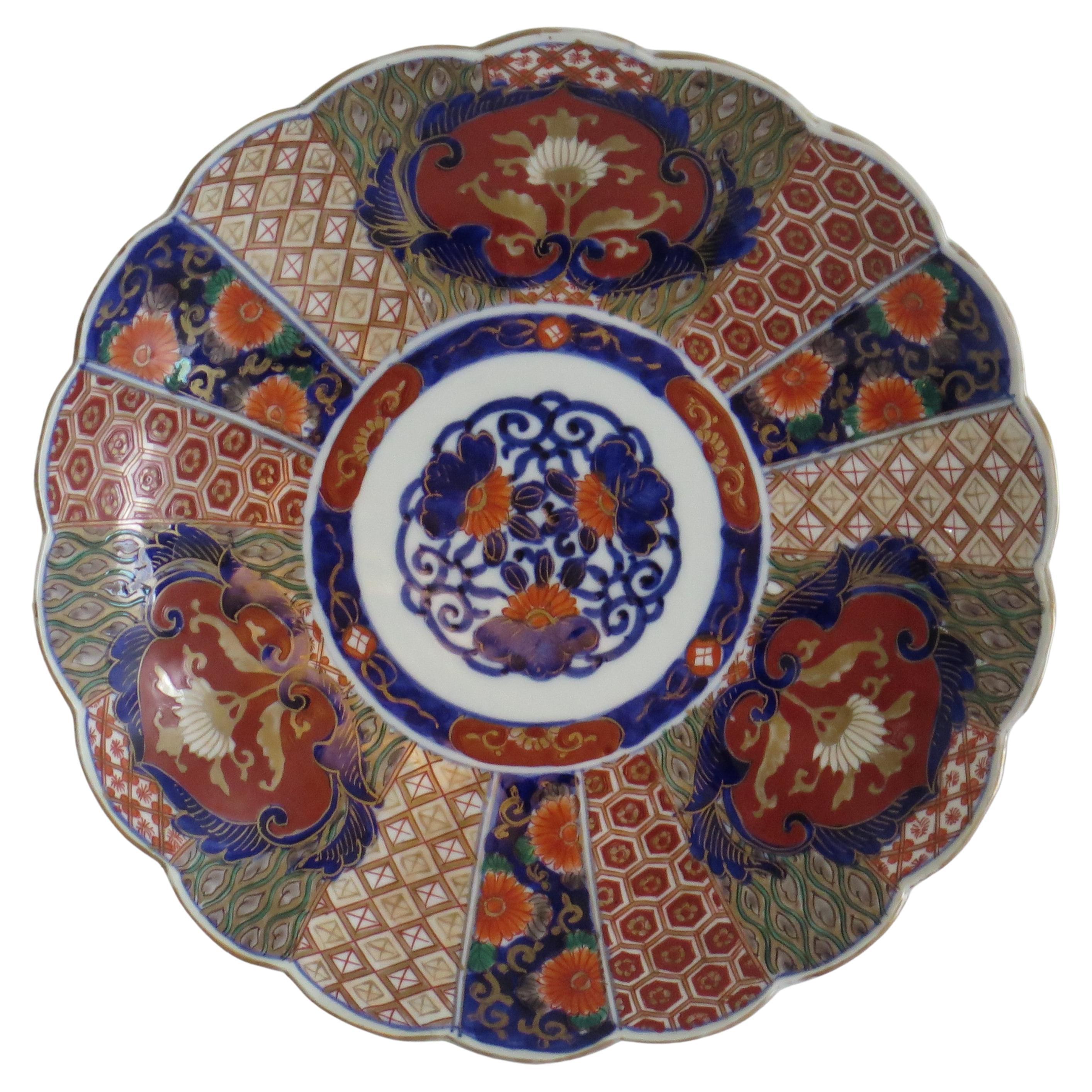 This is a good quality Japanese porcelain large plate or dish or charger with an Imari pattern, dating to the mid-late 19th century, Meiji period, circa 1870.

The plate or charger is well potted with a wavy rim and a lobed cavetto having 18