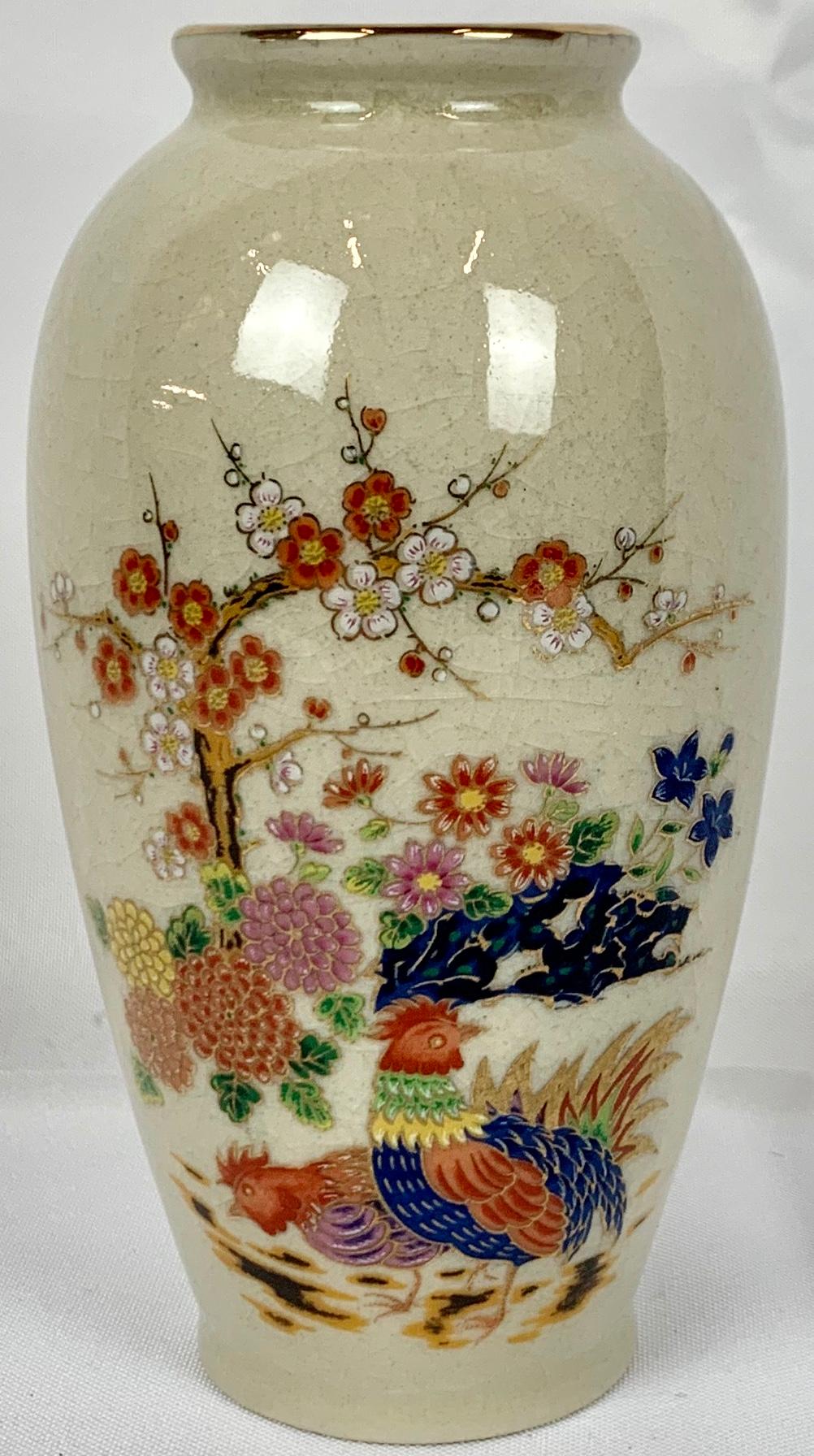 Japanese porcelain vase delicately hand painted on an craquelure oatmeal colored ground. The brightly colored design is of prunus blossoms, chrysanthemums and several roosters all outlined in gold. The top rim has been decorated with a gold