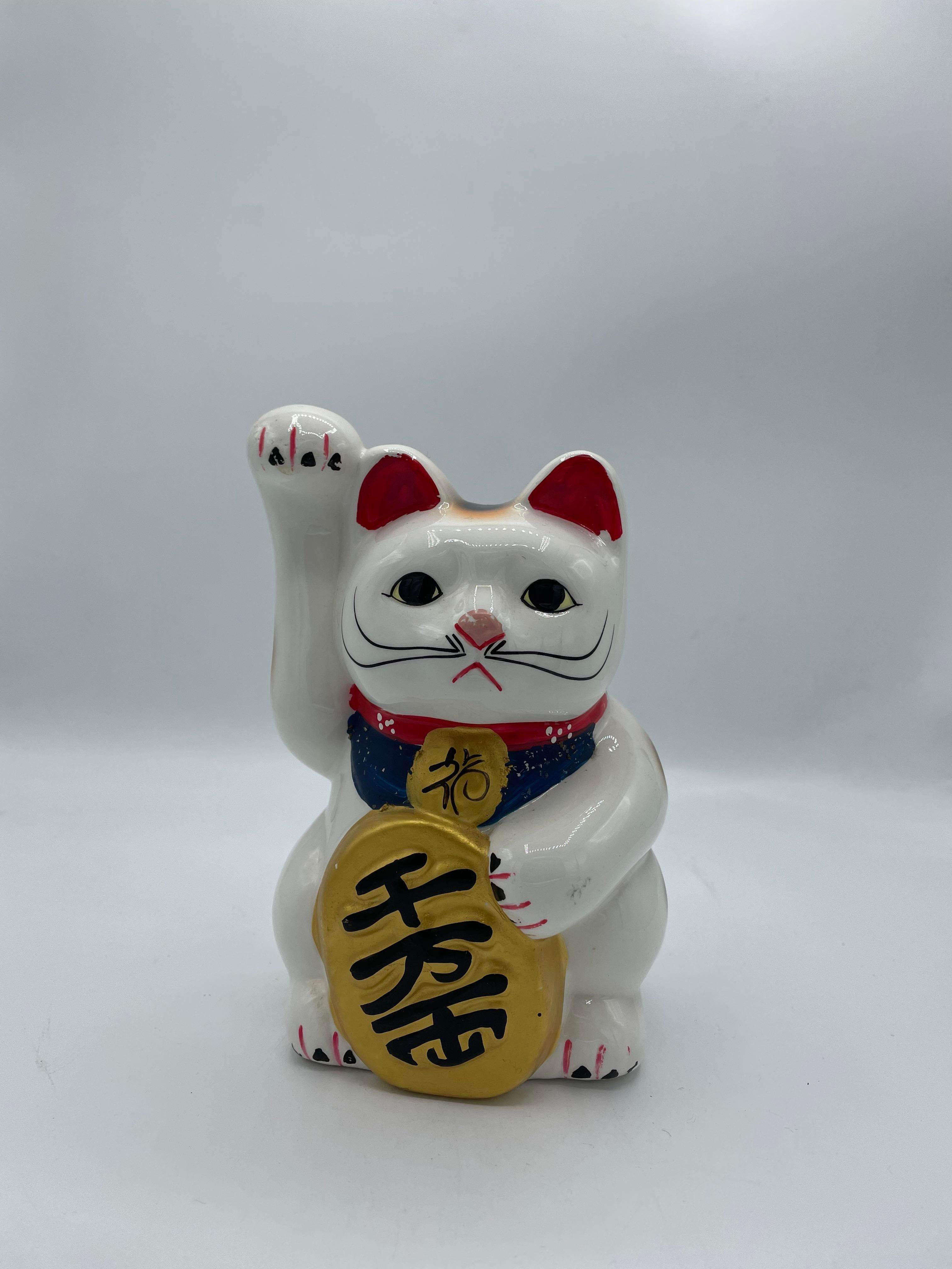 Voici une tirelire vintage représentant un chat manekineko. Elle est en porcelaine et a été fabriquée dans les années 1980, à l'ère Showa.

Le maneki-neko est une figurine japonaise courante dont on pense souvent qu'elle porte chance à son