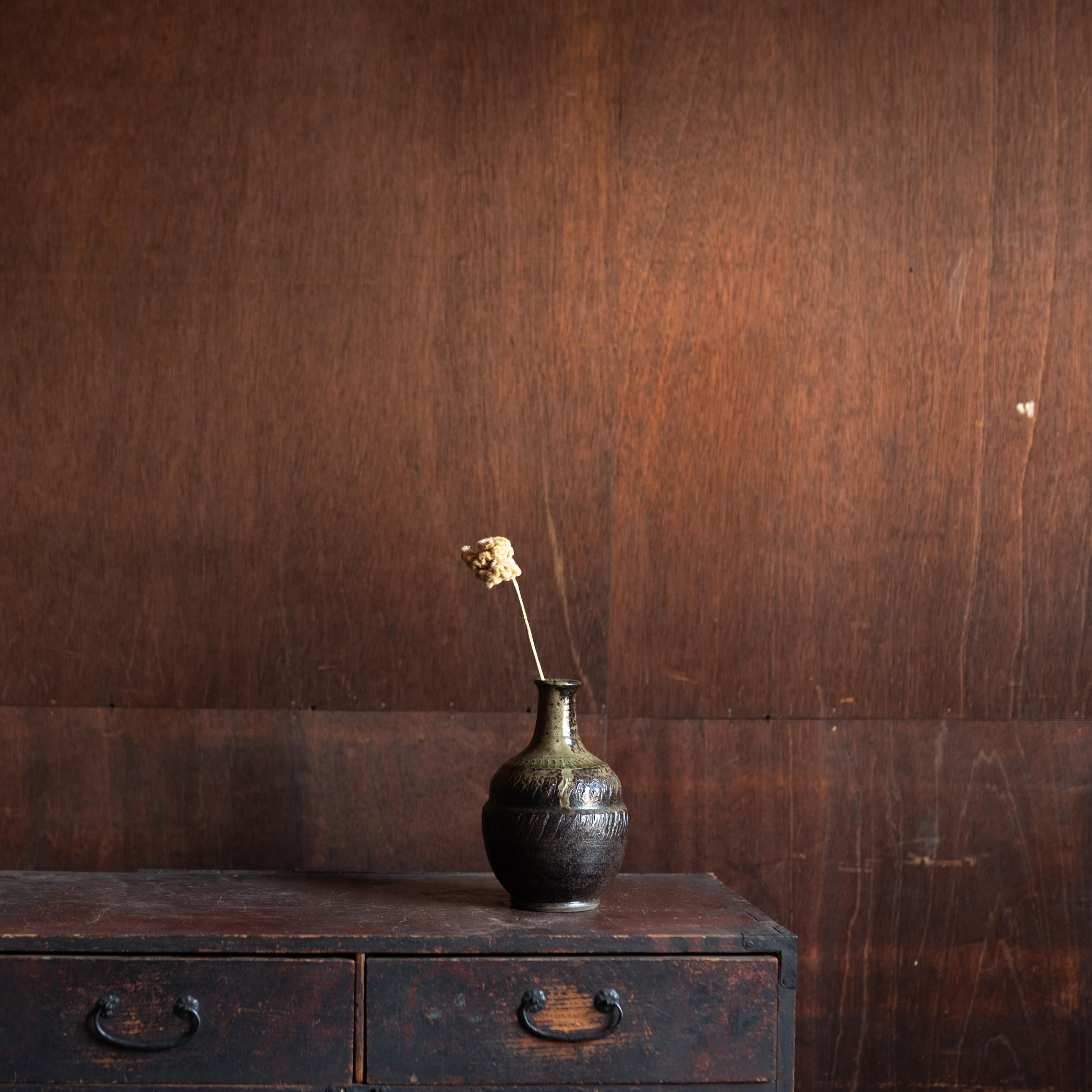 Japanese pottery vase, mid-20th century, with a strong sculptural presence and wabi-sabi character. The rounded body with a narrow neck recalls the form of a sake bottle (tokkuri), while the richly textured surface is finished in deep brown glaze