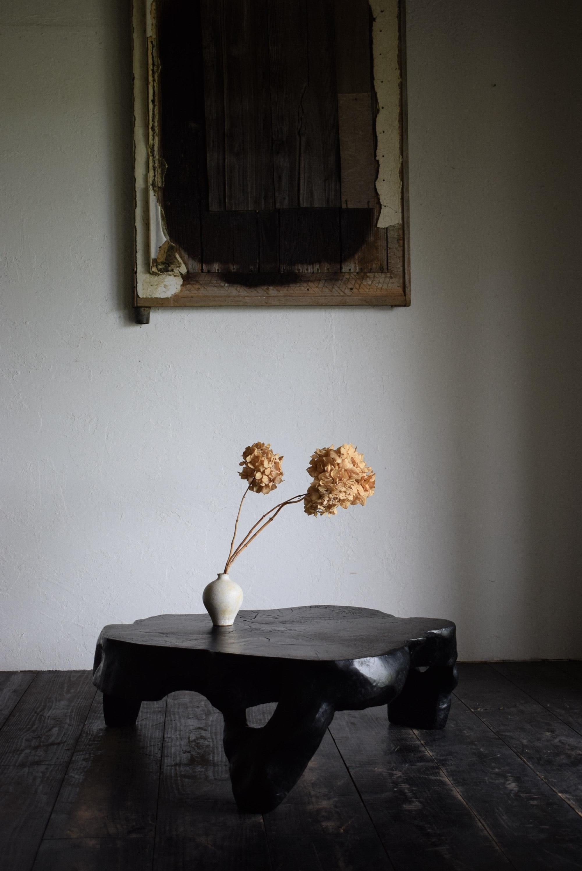 The three legs of this table are not attached, but are all made from the same tree stump. The surface is covered with cashew, which is a substitute for lacquer, and the black color is a very deep black color that gives off a Japanese feeling of