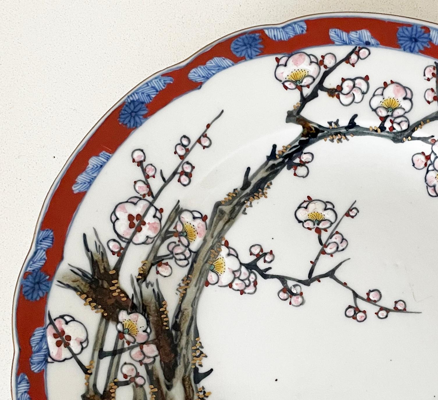 A beautiful Japanese plate with lightly fluted edges, decorated with flowering cherry blossom and two swifts in flight. With a vibrant red outer border decorated with flowers. In very good condition with no chips or cracks and minimal wear, dating