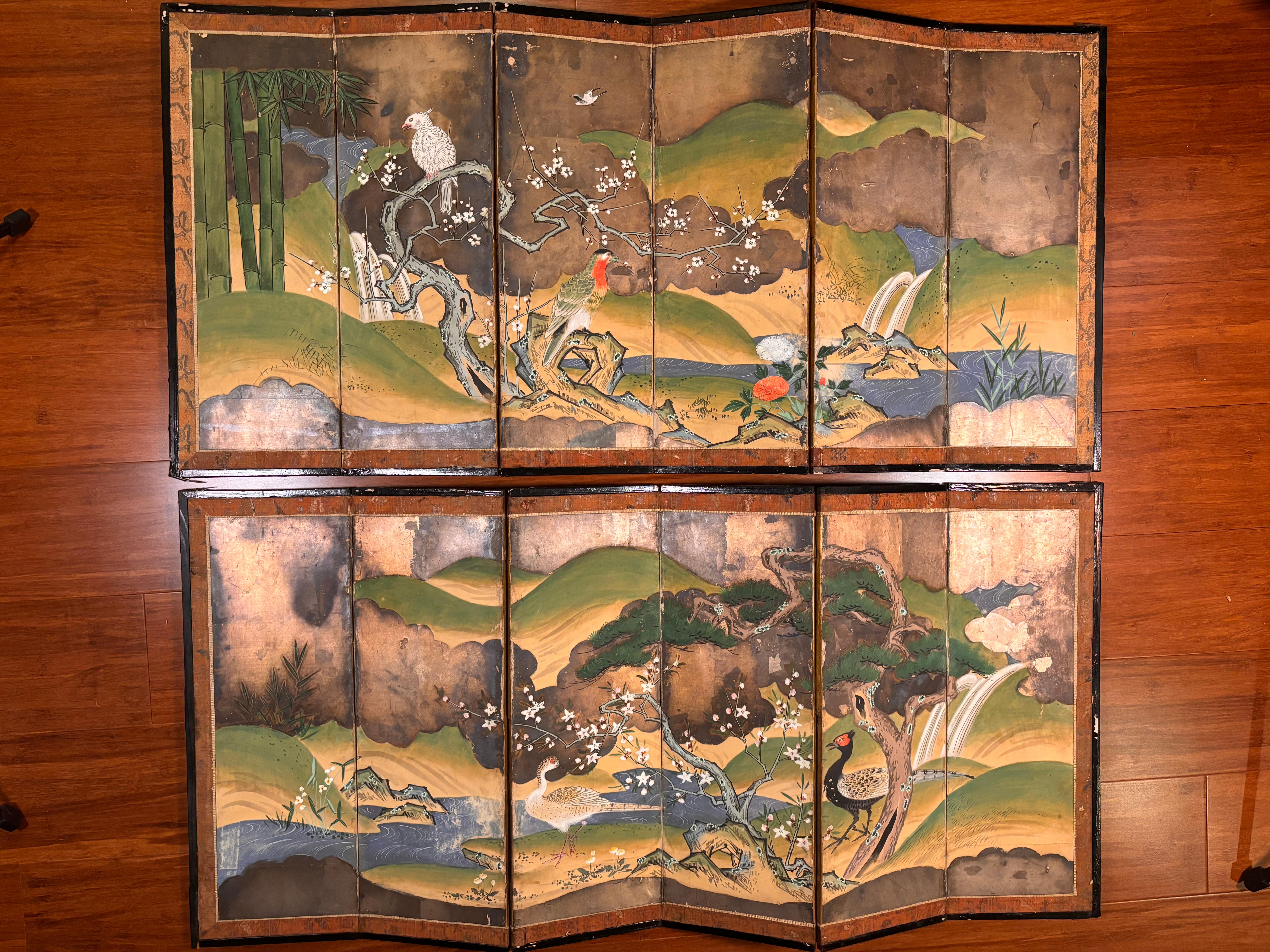A lovely antique pair (2) Japanese hand-painted six-panel folding screens byobu- each conceived in an attractive  birds, trees, and blue waters motif.  Likely given as a wedding gift , this pair includes showy pairs of birds in tree branches and