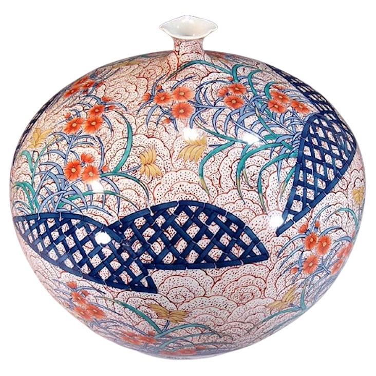 Exceptional contemporary Japanese Porcelain decorative vase, intricately hand painted in red, blue and cream on an ovoid shape body with an elegant scalloped rim, . It depicts a stunning flower motif set against a background with an elegant flower