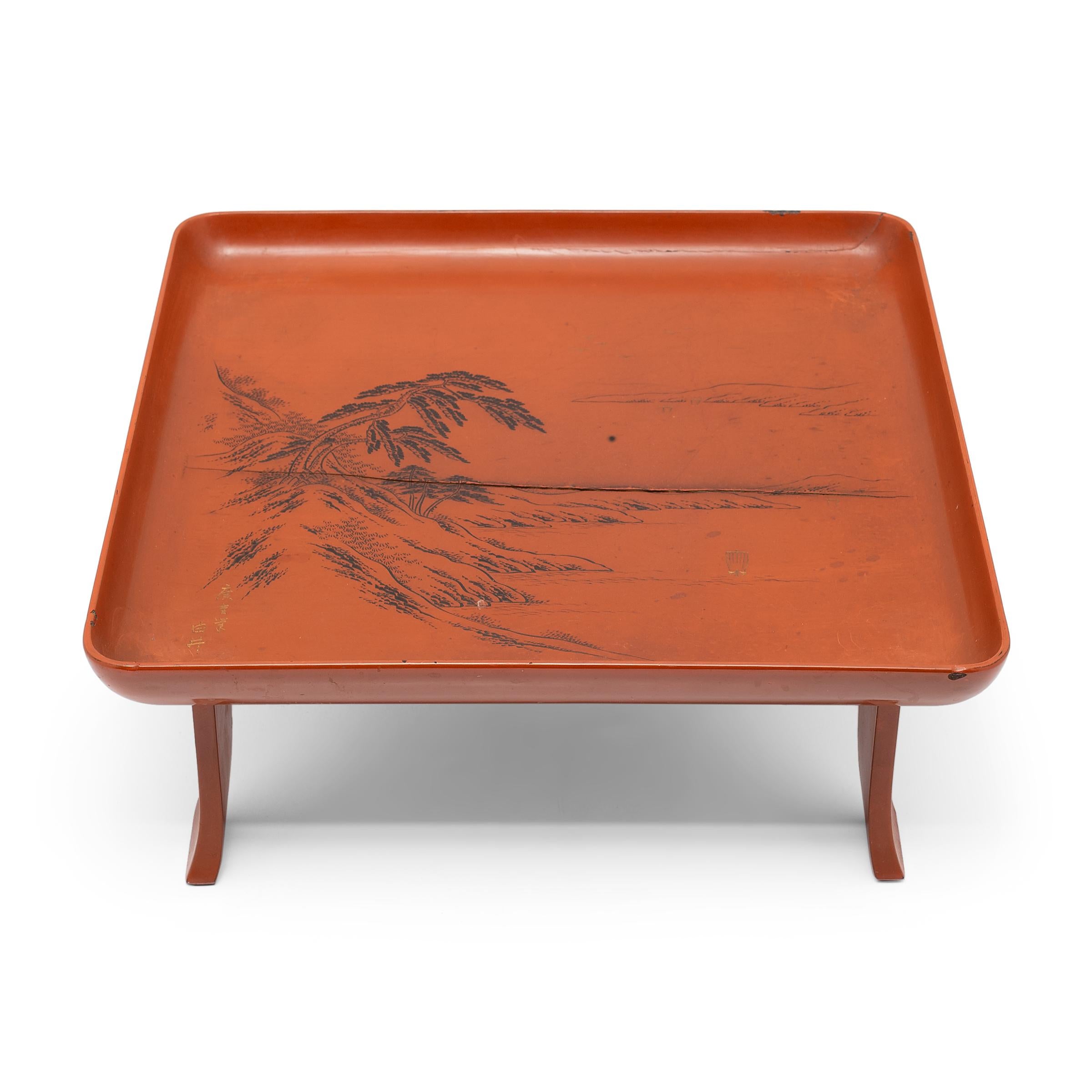 This Japanese serving tray exemplifies the refined style of Meiji-era lacquerware. Elevated by a splayed footed base, the tray has a shallow, square top with raised sides and rounded corners. The tray top is decorated with a serene sansui landscape,